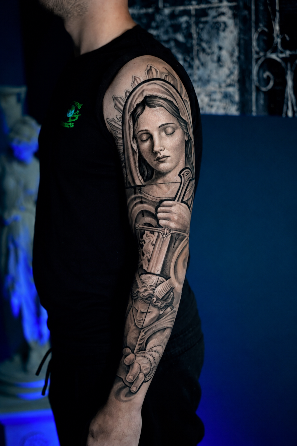 Black-and-gray warrior woman tattoo holding a sword with halo design at Black Craft Tattoo Collective.