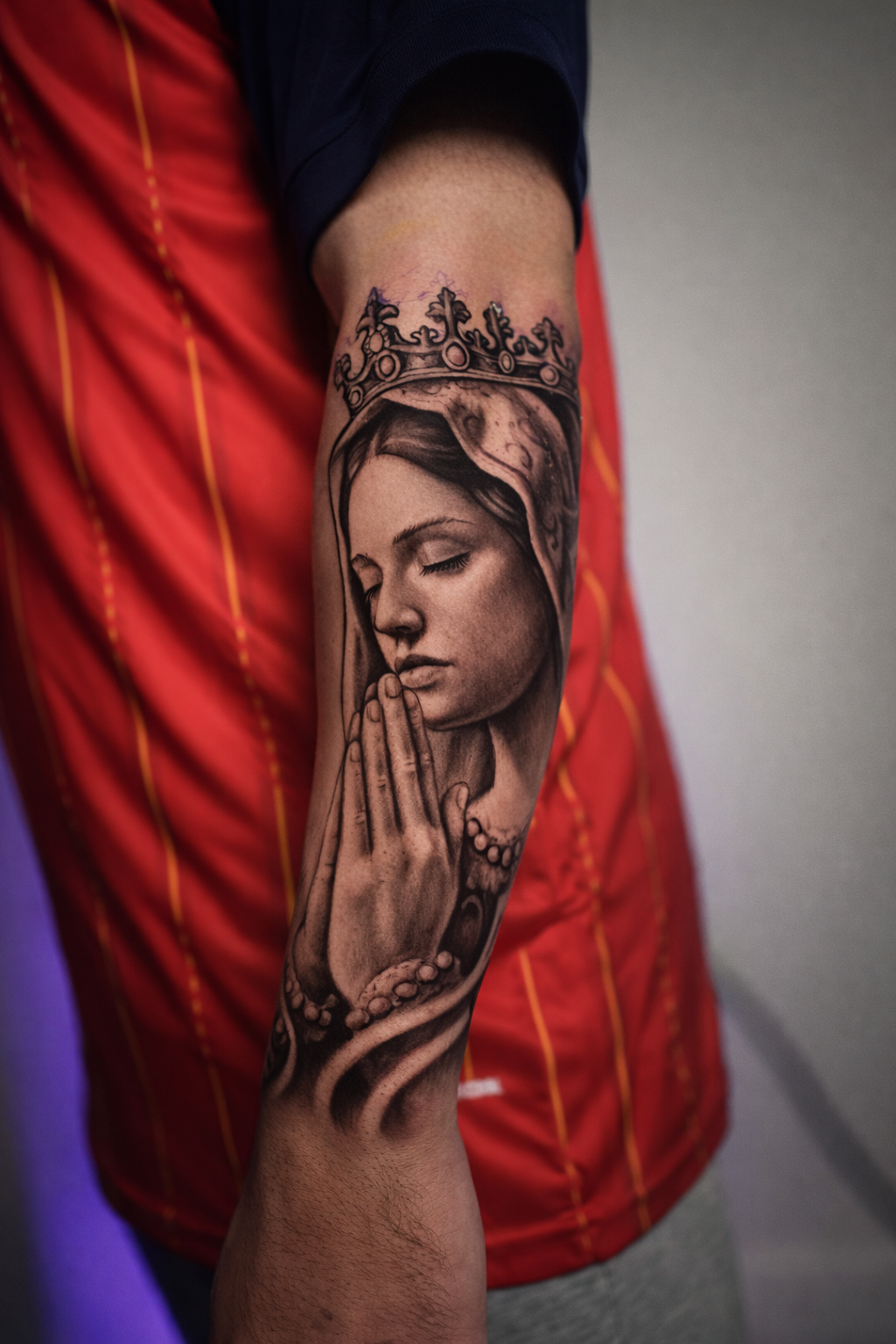 Black-and-gray crowned praying woman tattoo on the forearm at Black Craft Tattoo Collective.