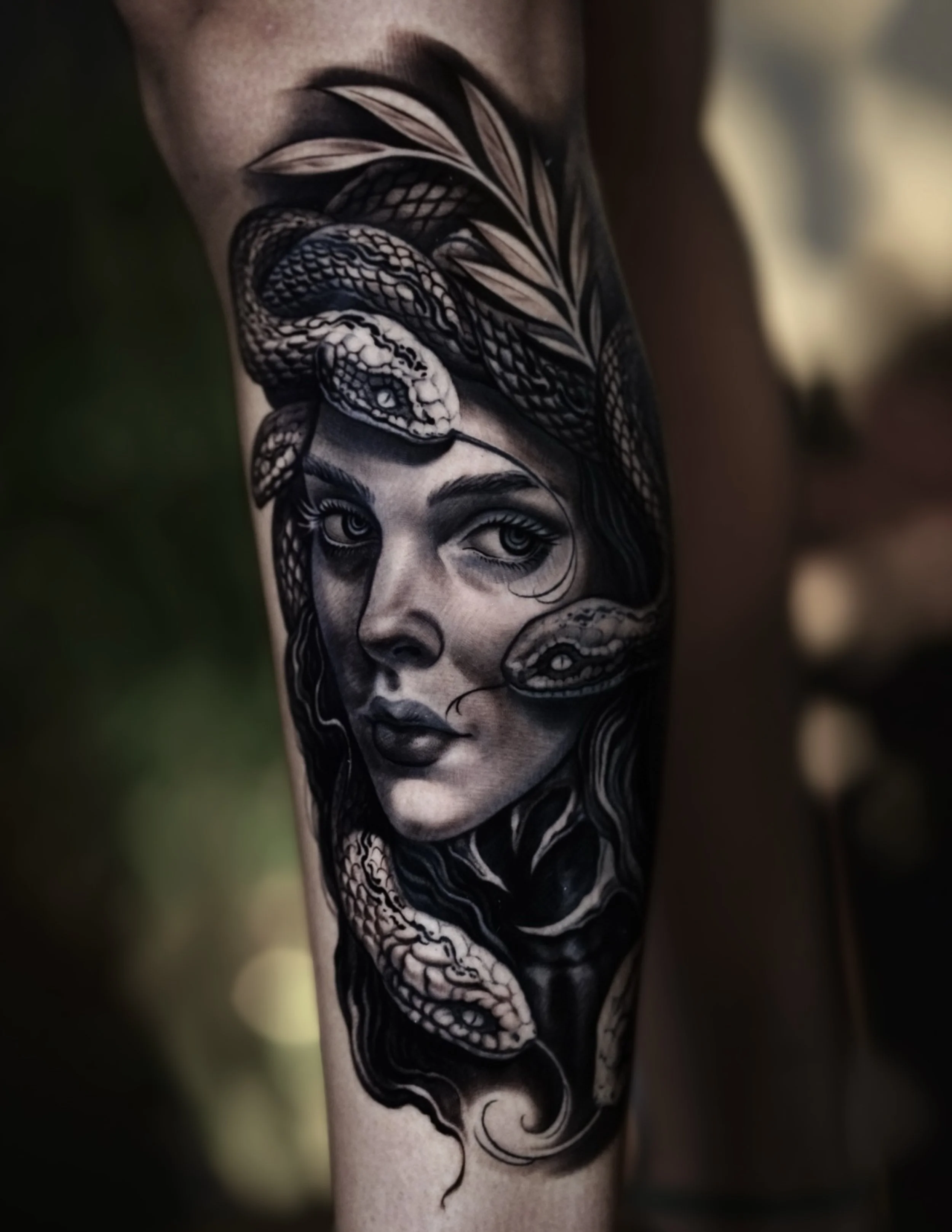 Black-and-gray woman portrait with a snake woven through her hair.