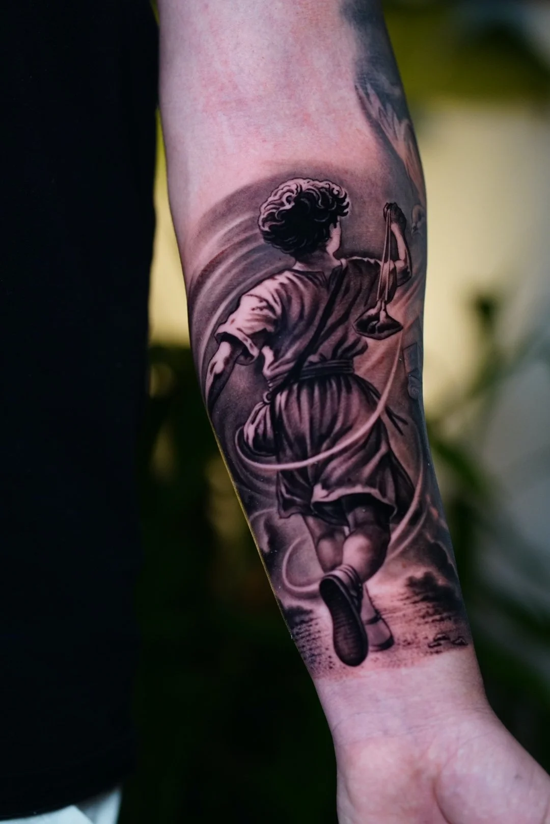 Black-and-gray Lady Justice tattoo holding scales and a sword.
