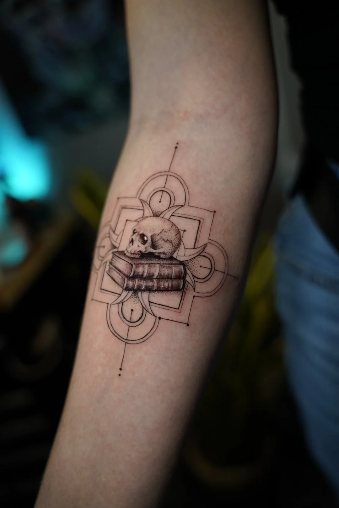 Detailed black-and-gray skull and books tattoo with geometric linework by Luis Dajer in Charlotte, NC.