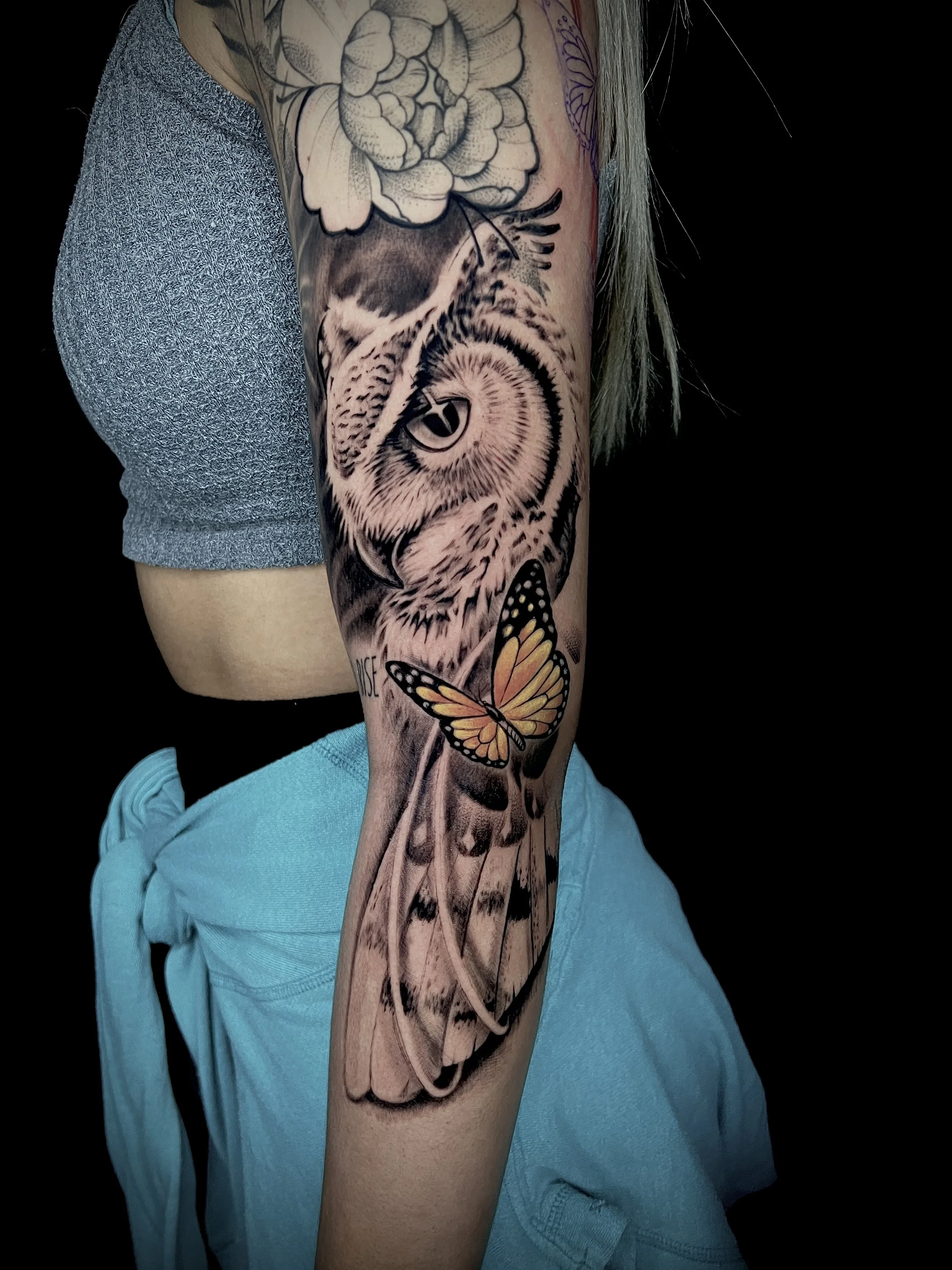 Black-and-gray owl, flower and butterfly upper-arm tattoo by Luis Dajer.