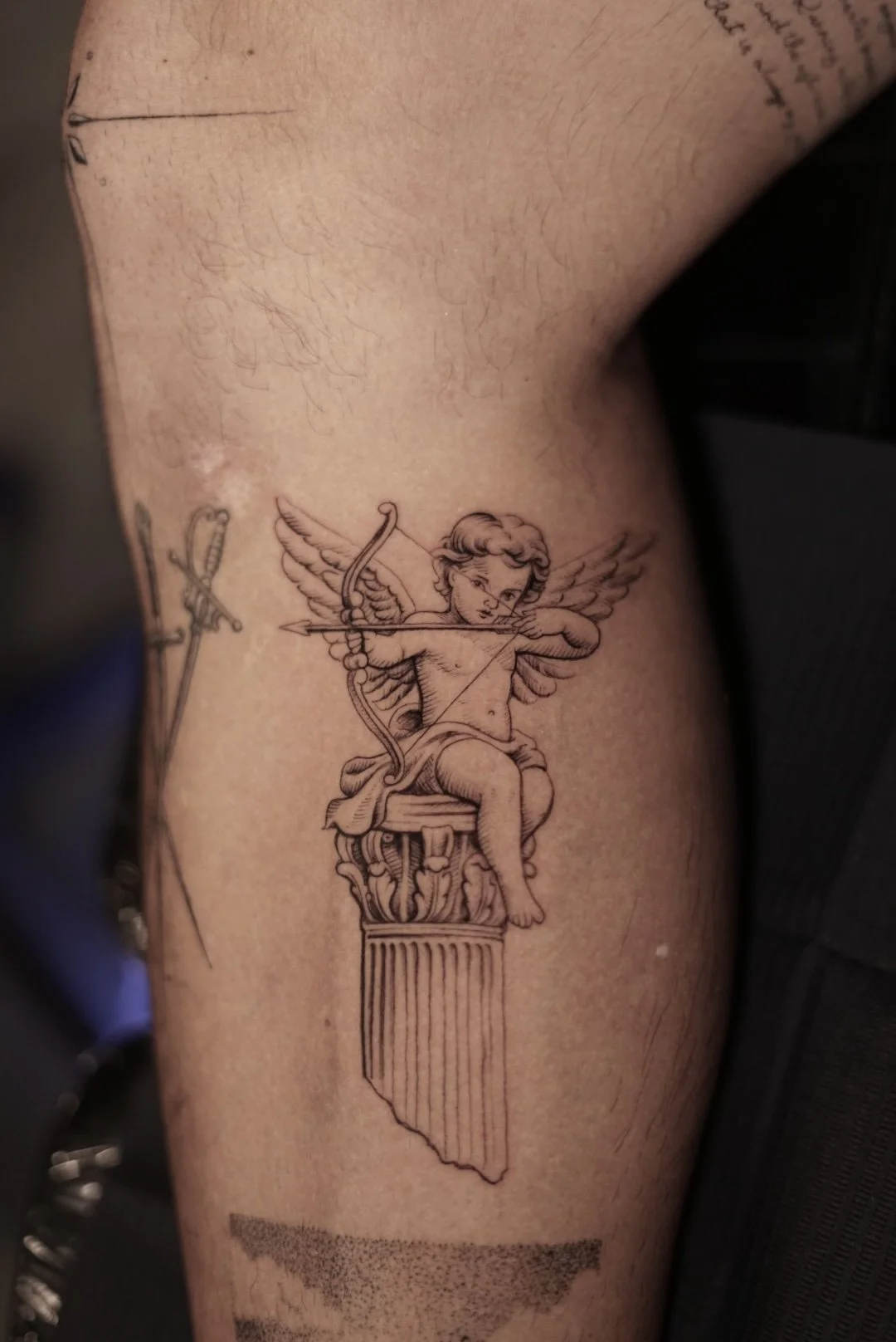Fine-line Cupid drawing a bow from a classical column tattoo.