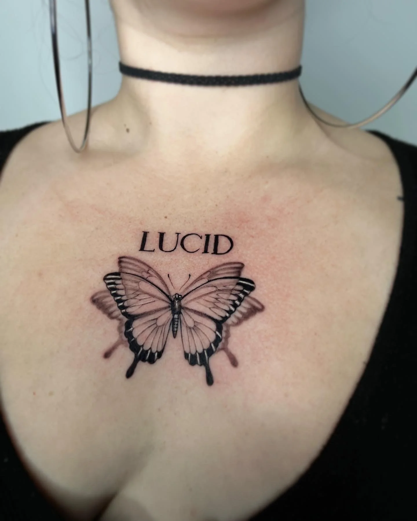 Fine-line butterfly and LUCID lettering chest tattoo by Luis Dajer.