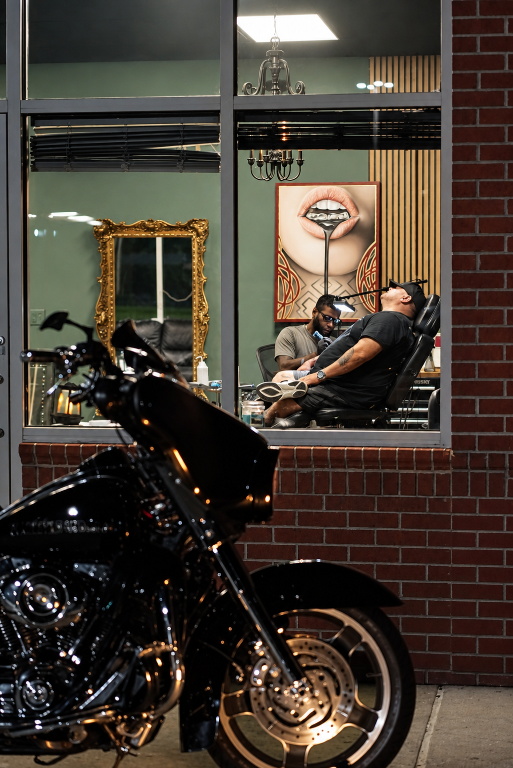 Luis Dajer tattooing inside Black Craft Tattoo Collective, photographed through the studio window.