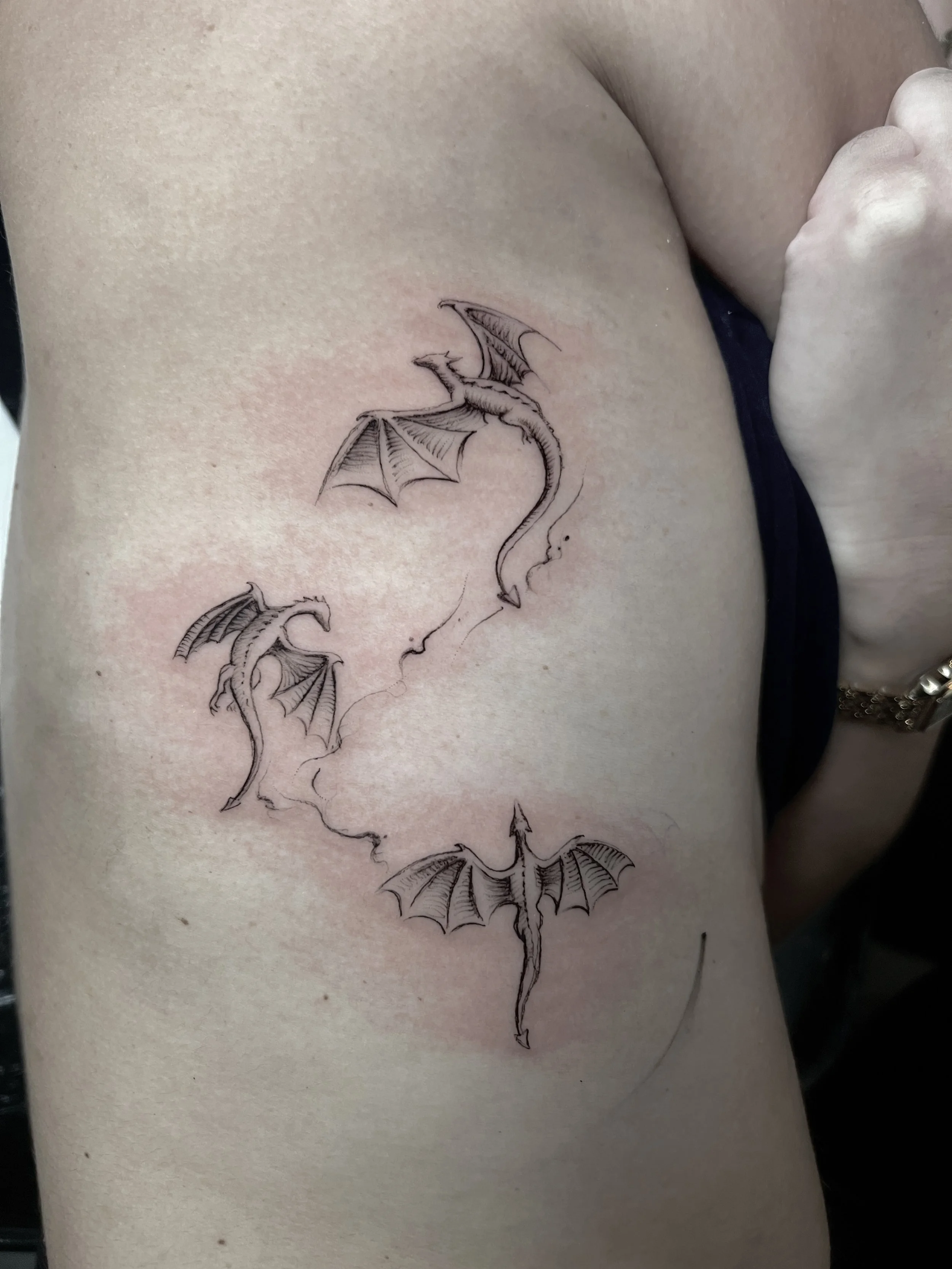 Fine-line flying dragons tattoo on the chest by Luis Dajer.