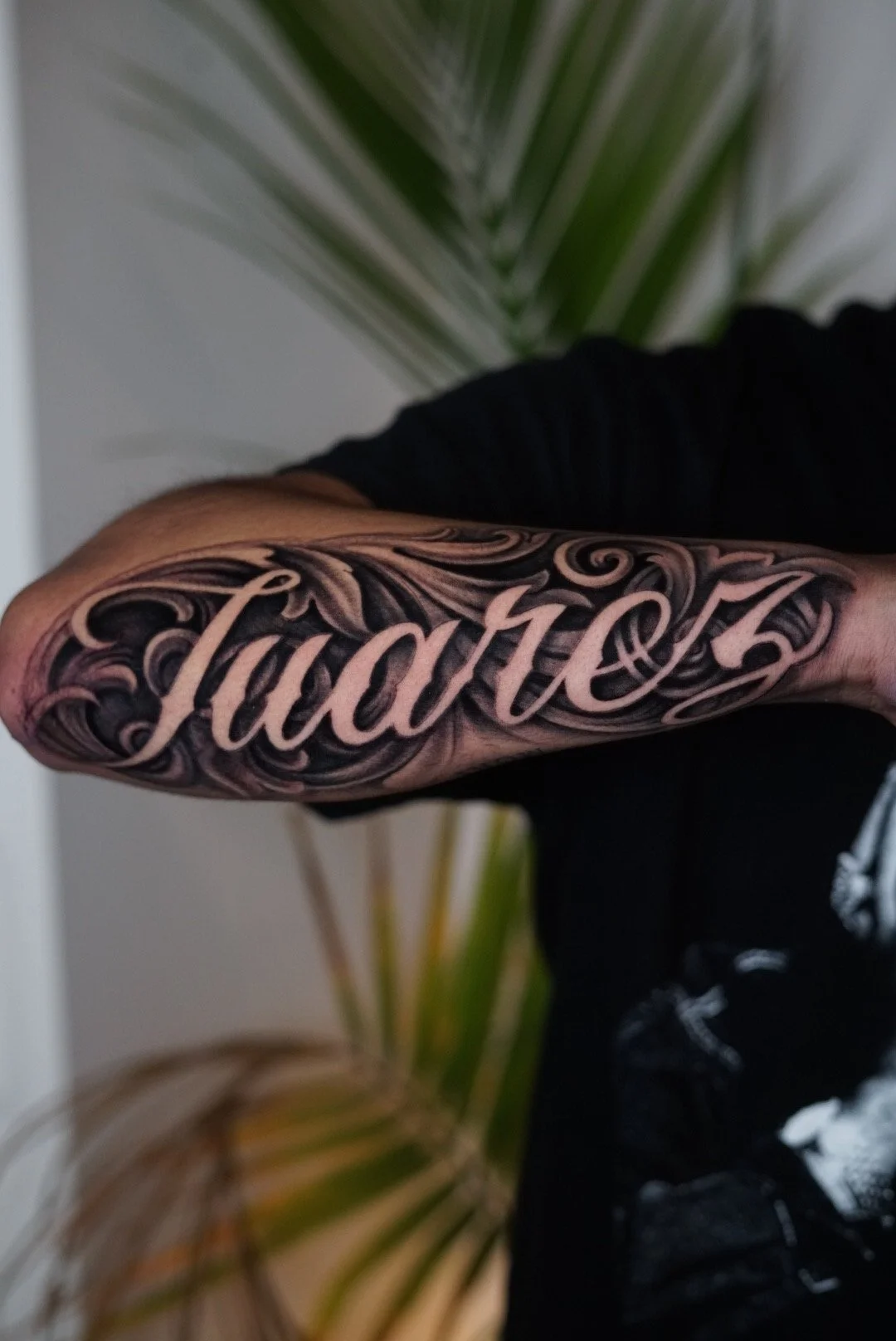 Justice script forearm tattoo with decorative black-and-gray flourishes in Charlotte, NC.