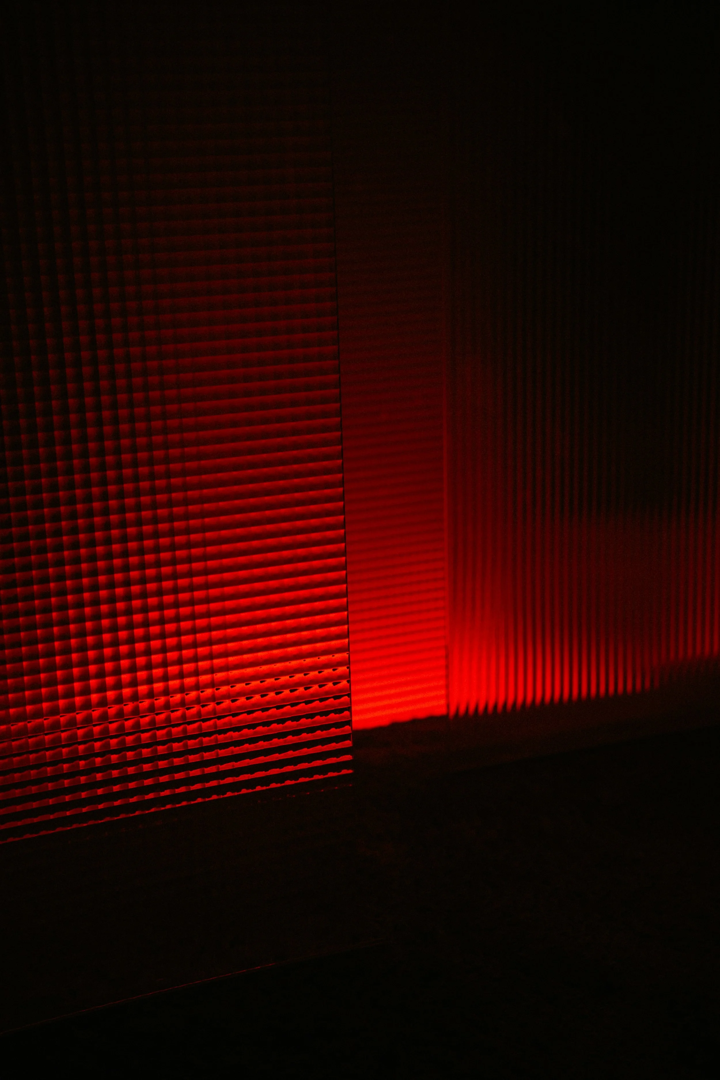 Close-up of textured, ribbed metal panels illuminated by red light.