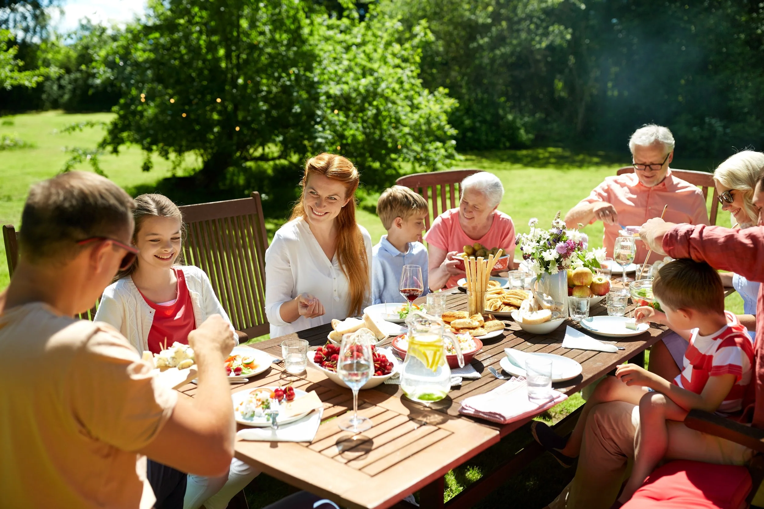 Multi-generational family enjoying an outdoor meal together in the backyard of an Arizona home, reflecting family life and homeownership in Arizona.