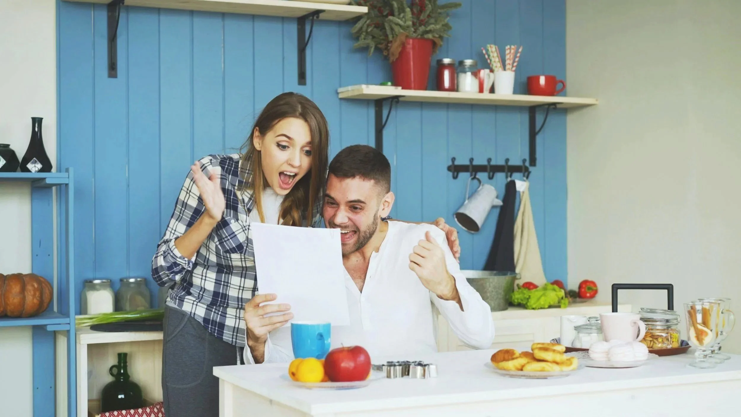 Couple celebrating good news in the kitchen of their Arizona home, reflecting the excitement of homeownership and financial milestones.