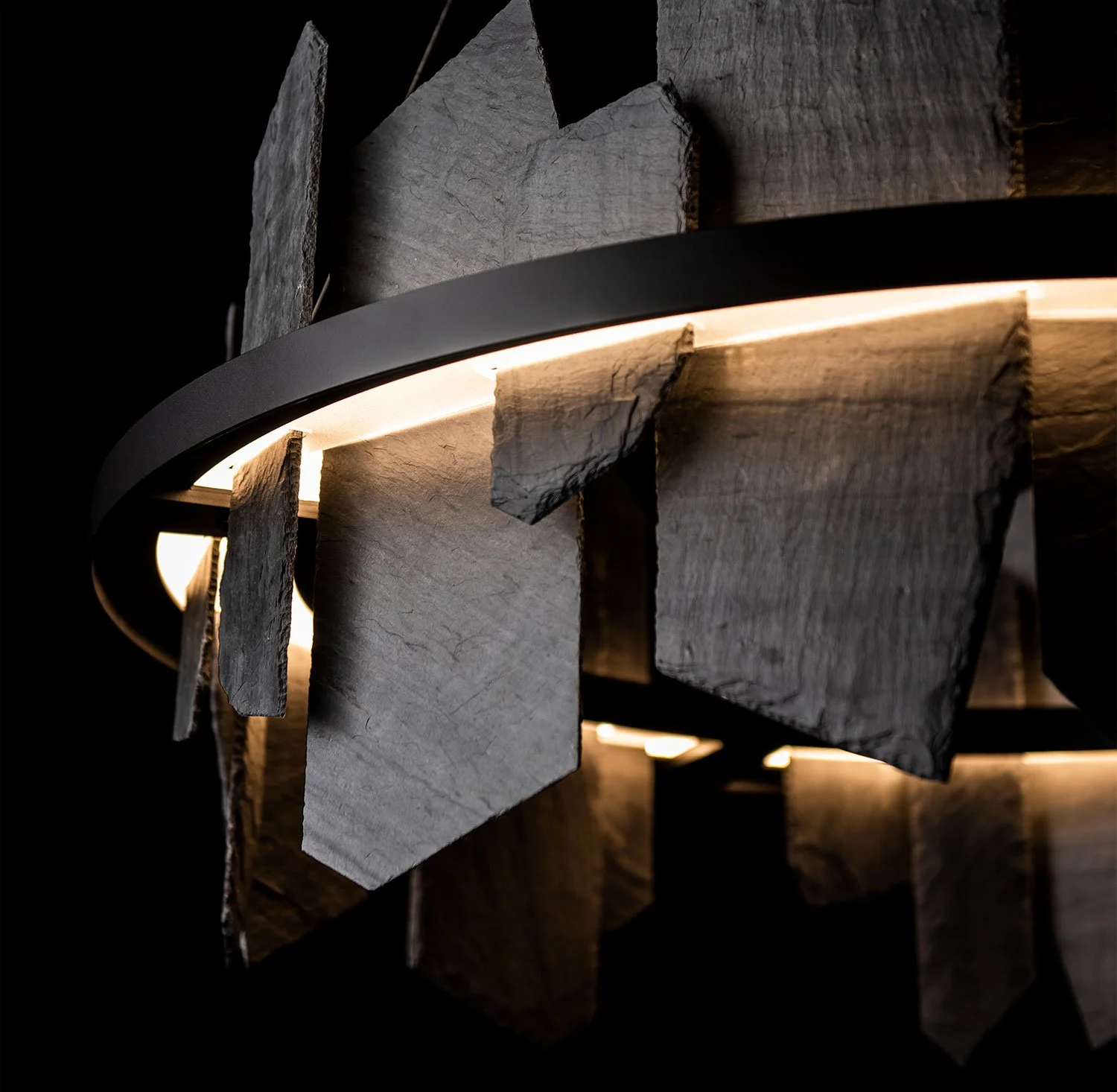 Close-up of a modern light fixture made of stone and metal, with warm lighting behind the stones.