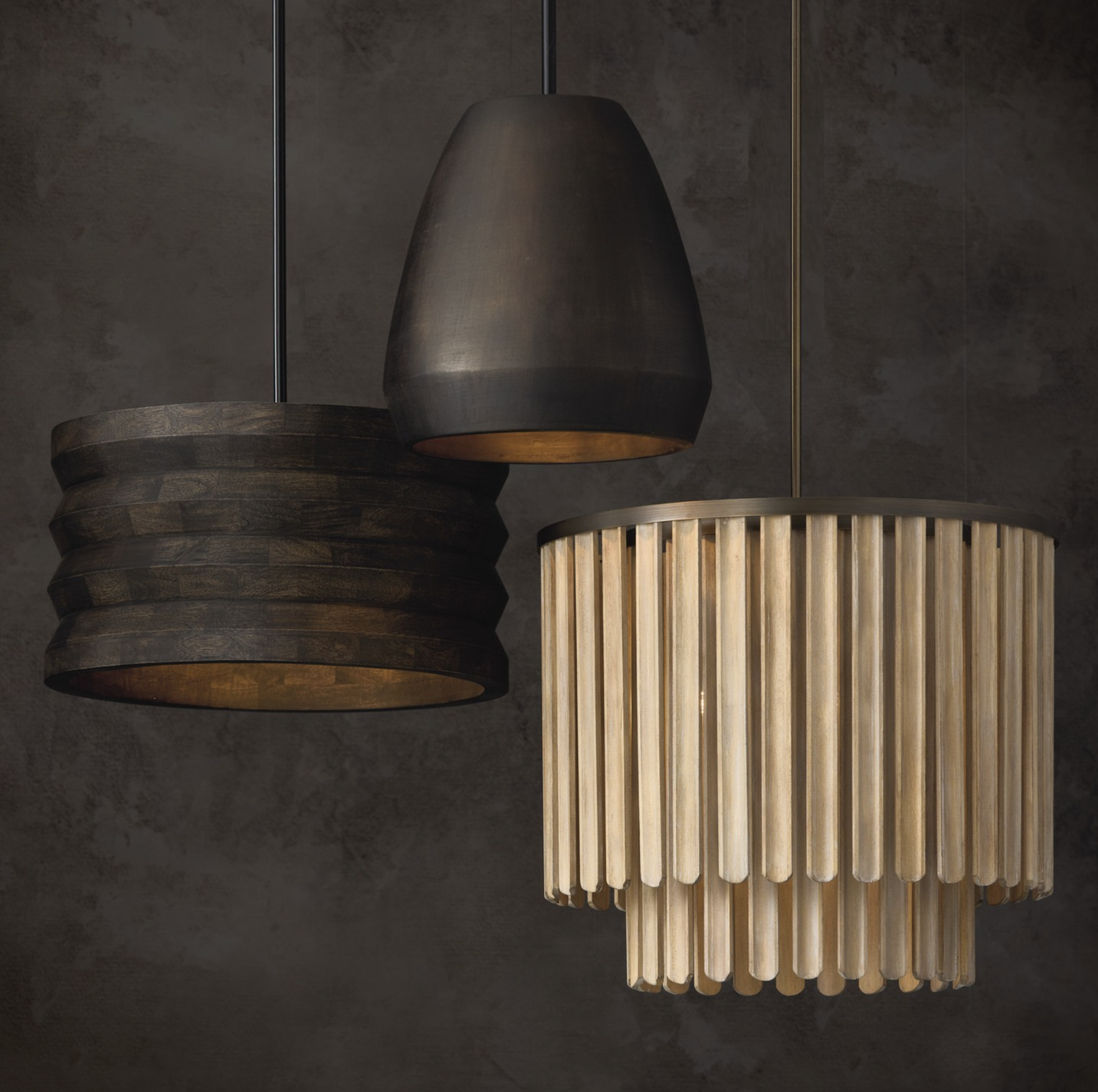 Close-up of three hanging pendant lights with different shades: white, white with a scalloped edge, and metallic gold, against a dark background.