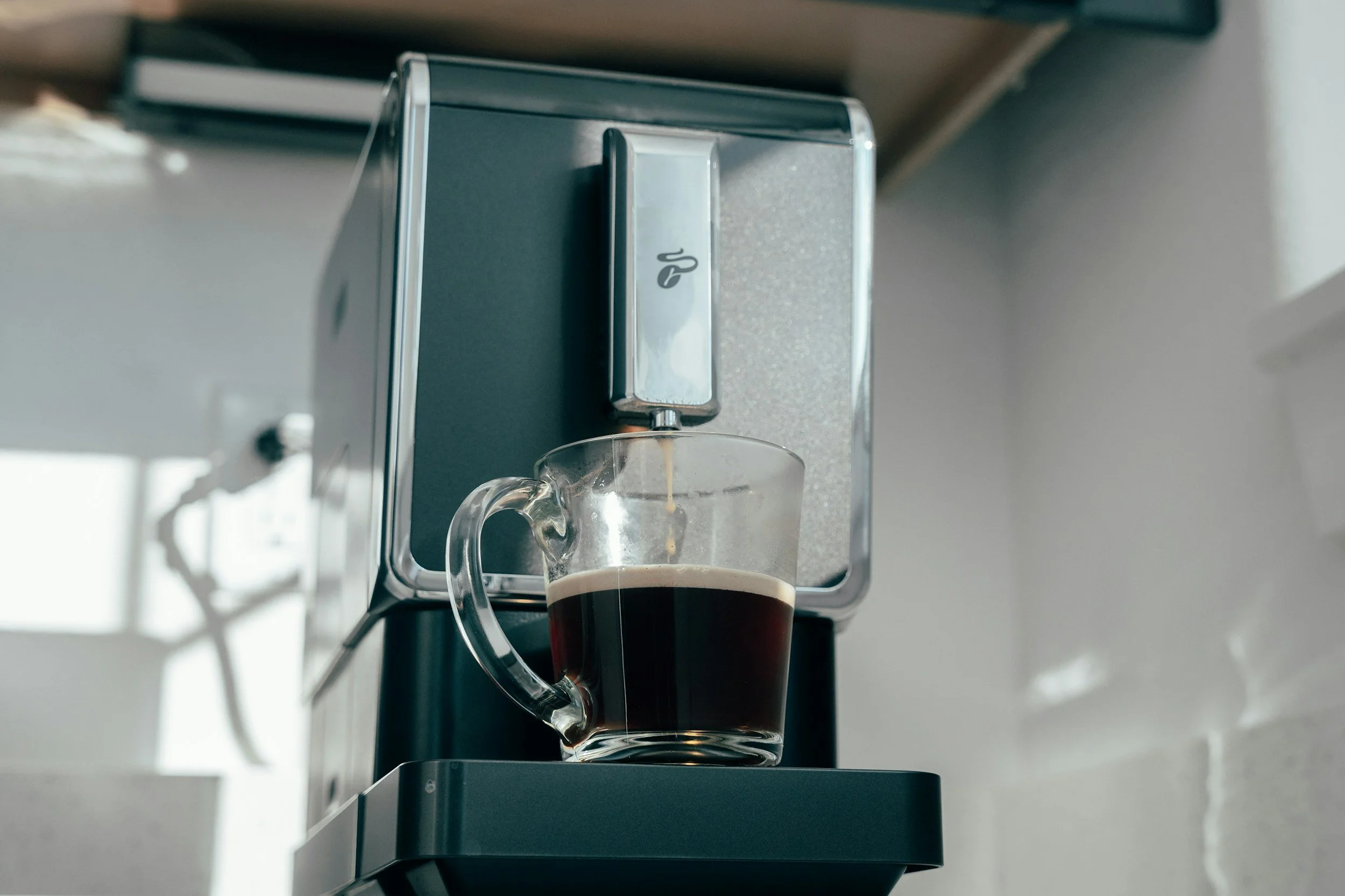 A coffee maker brewing coffee into a glass mug.