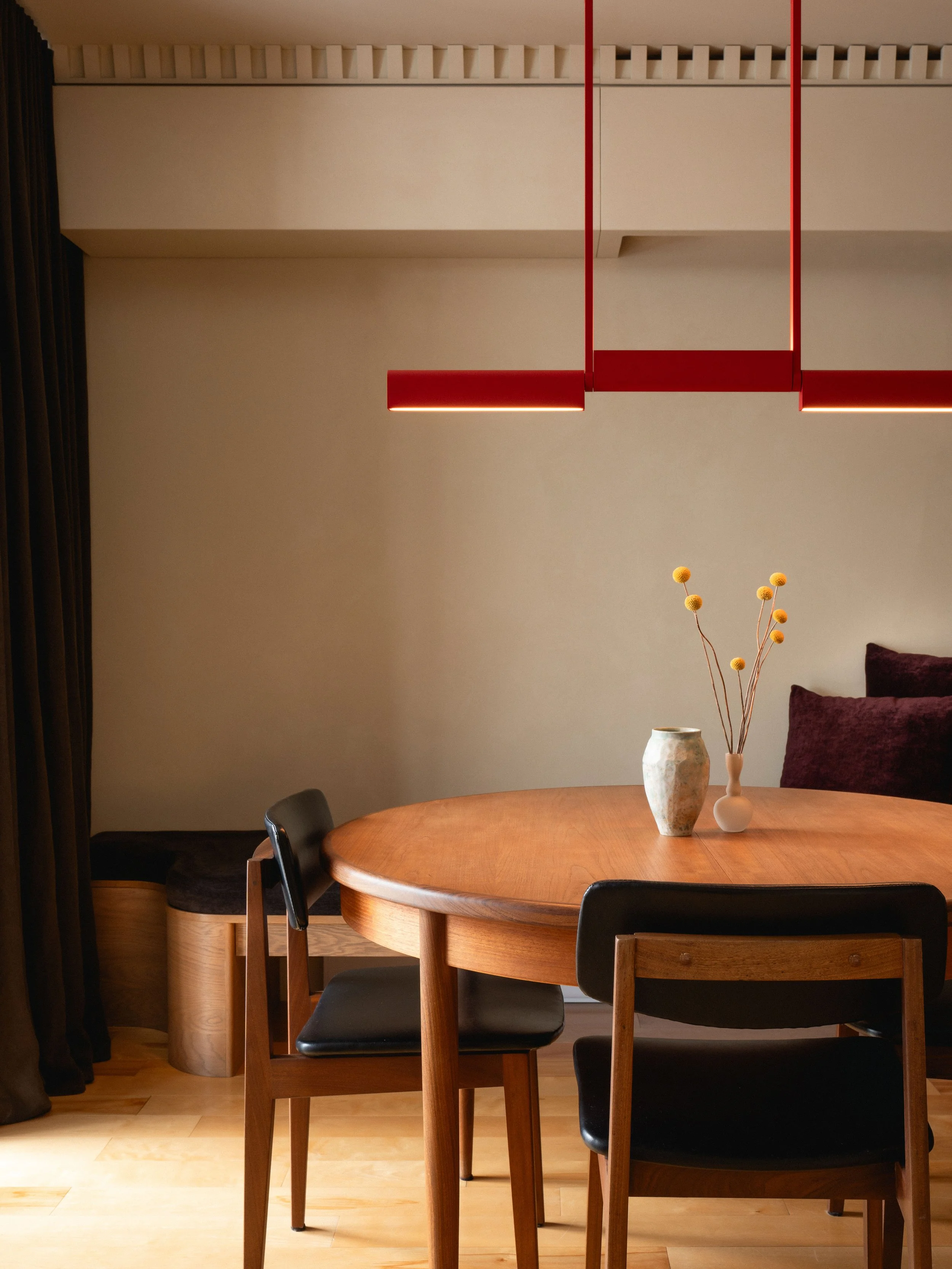 Salle à manger d'une résidence rénovée, mettant en valeur des matériaux naturels, du mobilier sur mesure et une lumière douce.