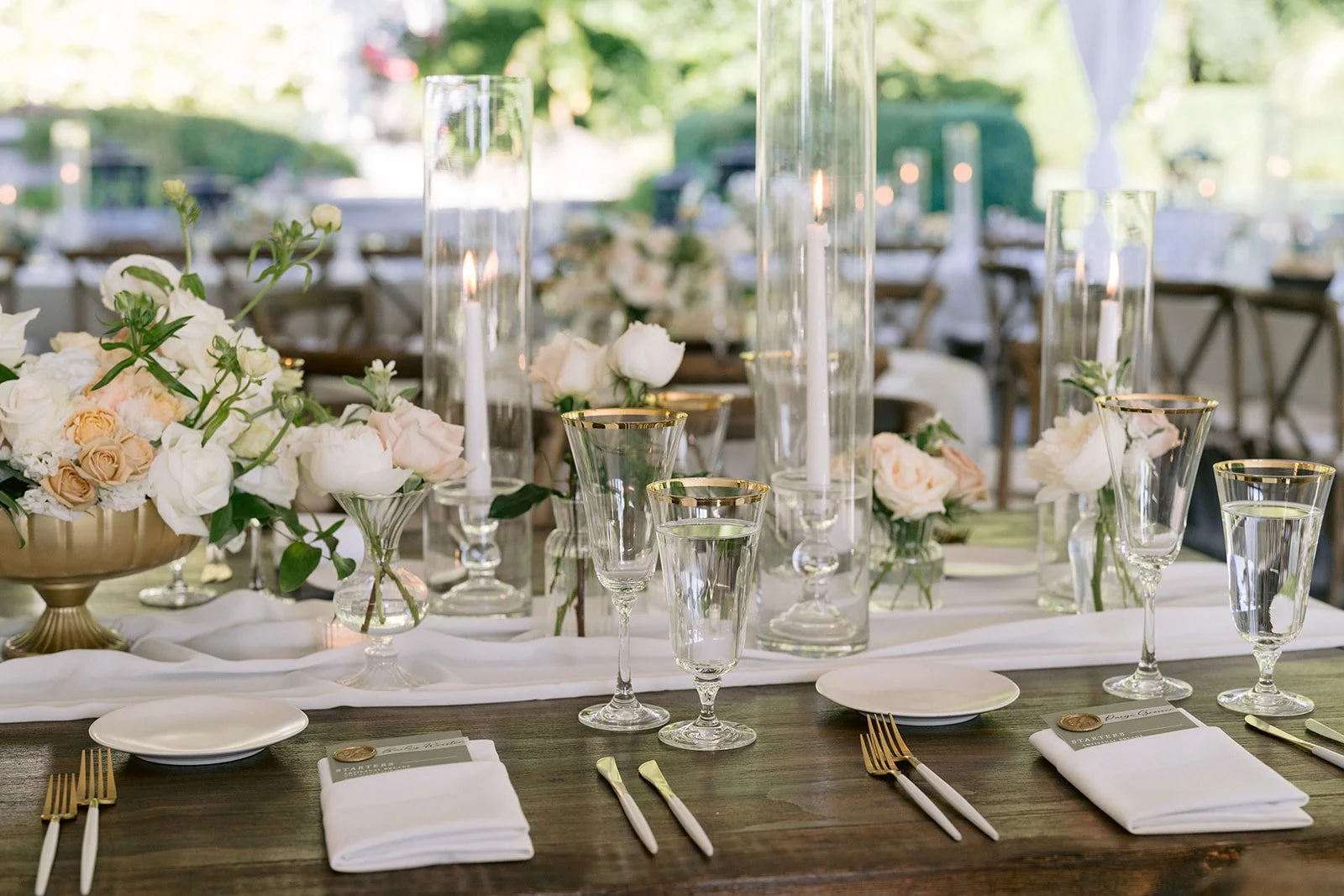Elegant outdoor table setting with white flowers, candles, glassware, and gold-rimmed plates and utensils - Chateau Lill, Snohomish WA — Gordon Duo Weddings, photo by Erica Streelman