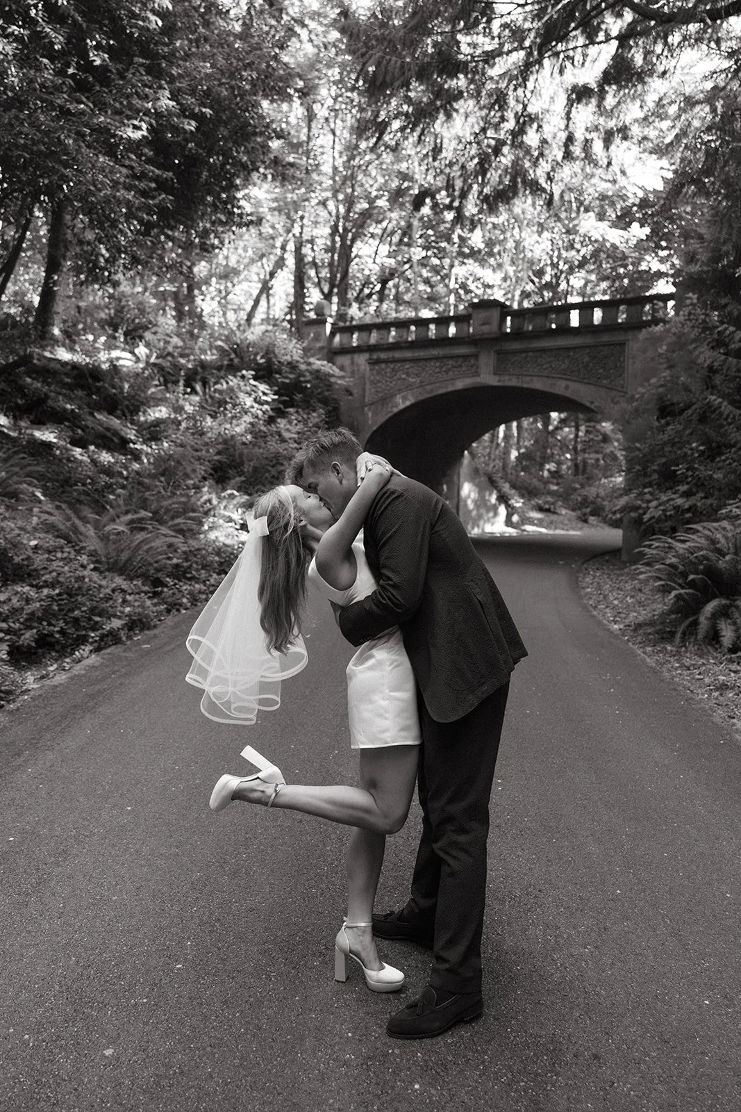 Bride and groom kissing on stone bridge in black and white at The Highlands Shoreline — wedding planned by Gordon Duo Weddings