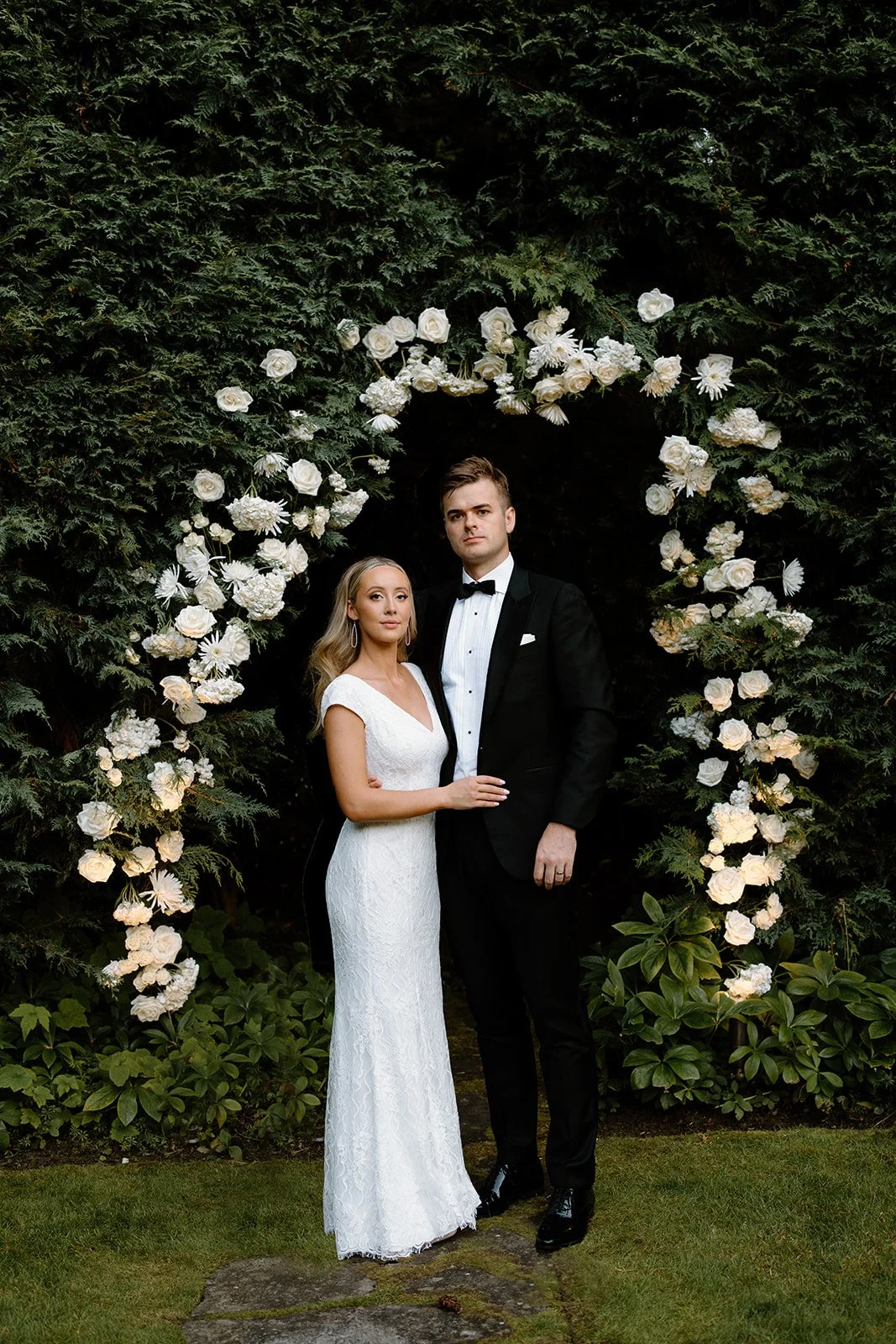 Bride and groom under floral arch at The Highlands Shoreline — wedding planned by Gordon Duo Weddings
