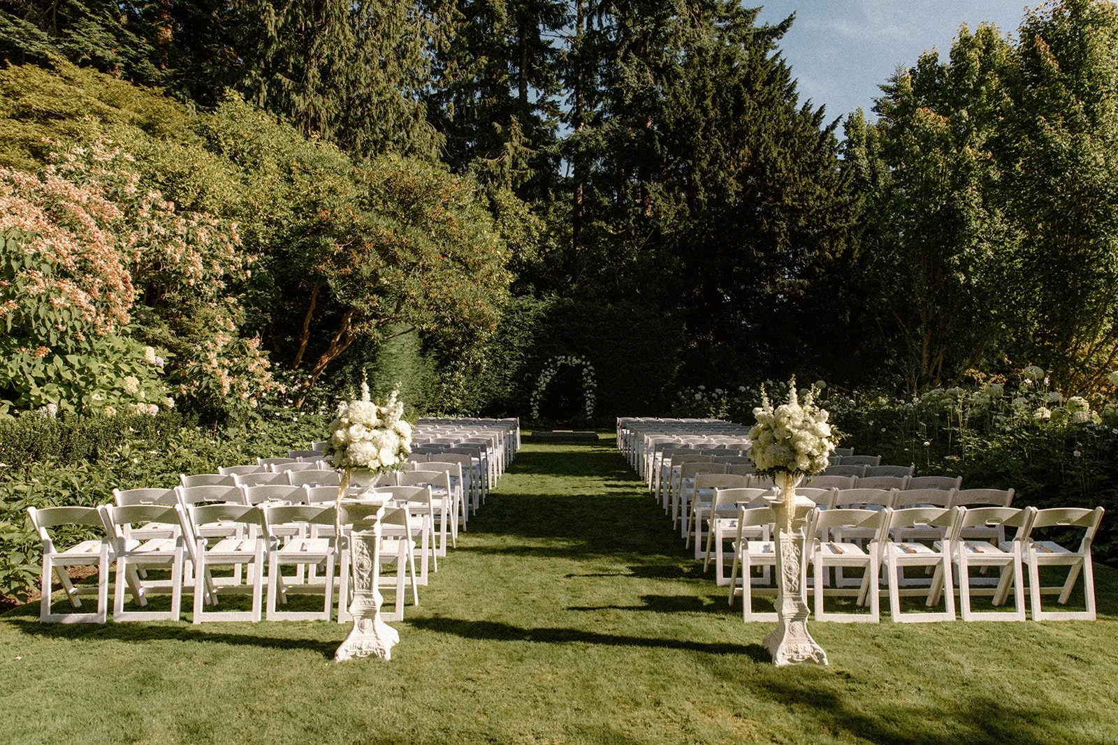 Outdoor ceremony setup with white chairs and garden greenery at The Highlands Shoreline — wedding planned by Gordon Duo Weddings