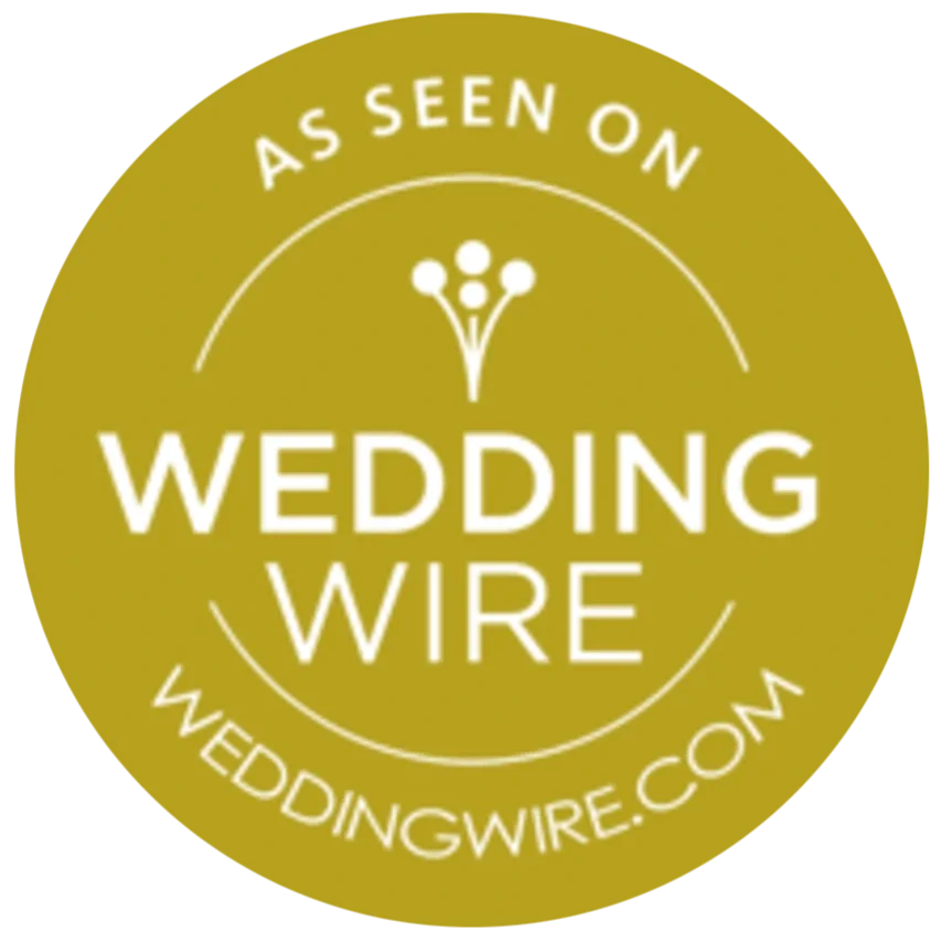 Gold circular badge with white text that says "As seen on Wedding Wire" and includes the website weddingwire.com, with a simple flower icon at the top.
