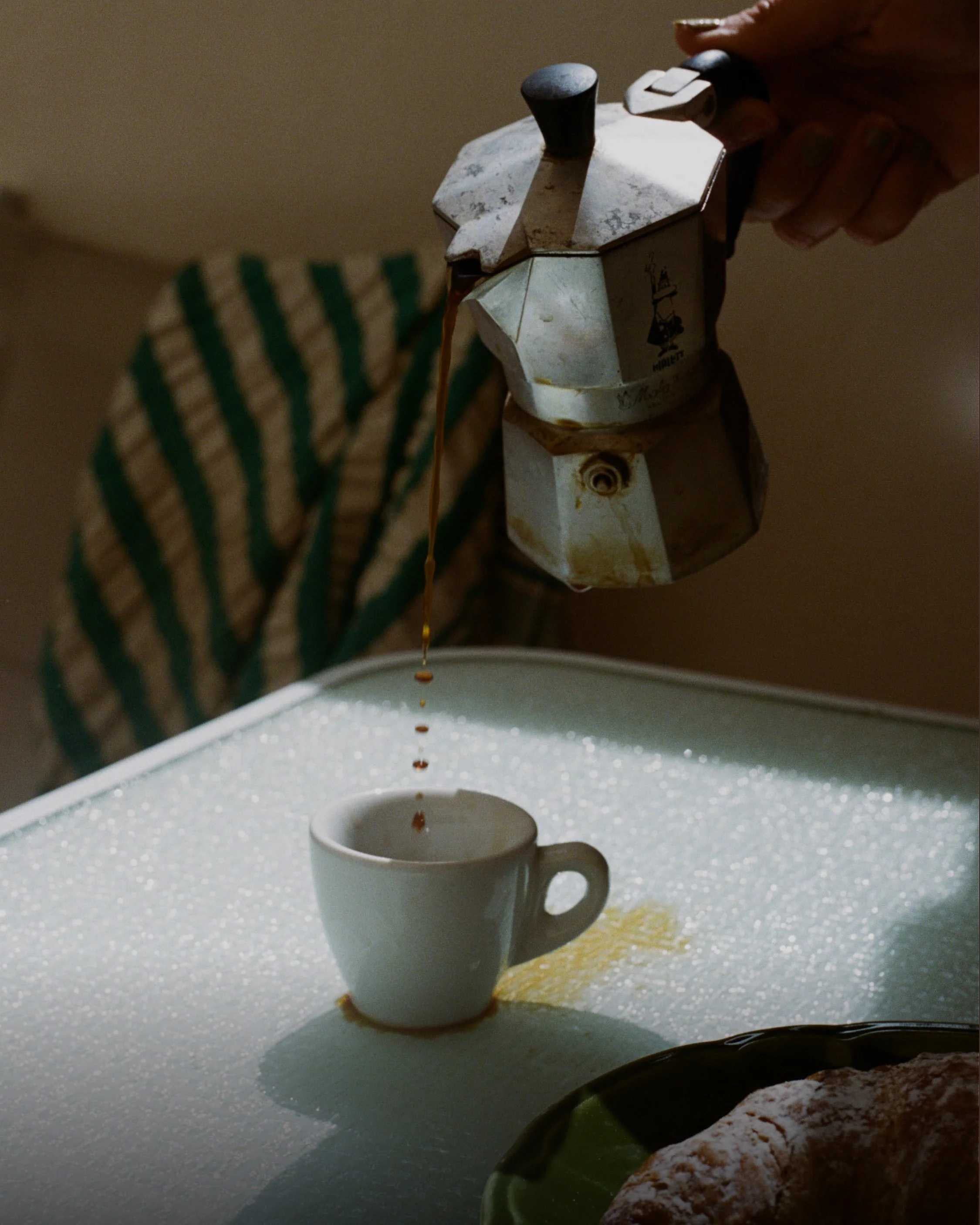 Image of a coffee pitcher pouring hot black coffee into a coffee cup