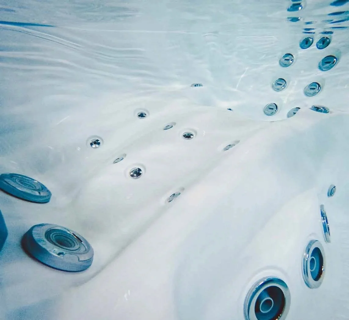 Close-up of a hot tub or Jacuzzi with multiple circular jets embedded in the white interior surface.
