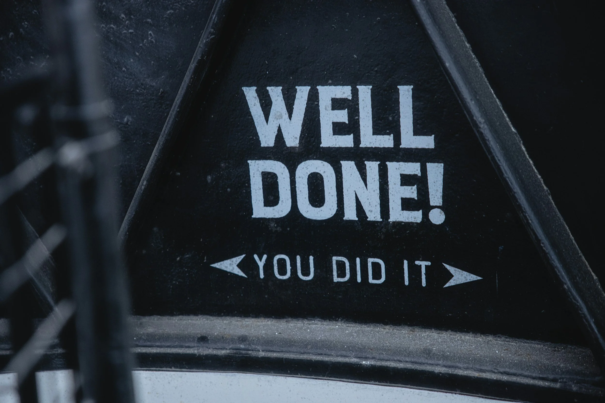 A black surface with large white text that reads 'WELL DONE!' and a small arrow pointing left with text saying 'YOU DID IT'.