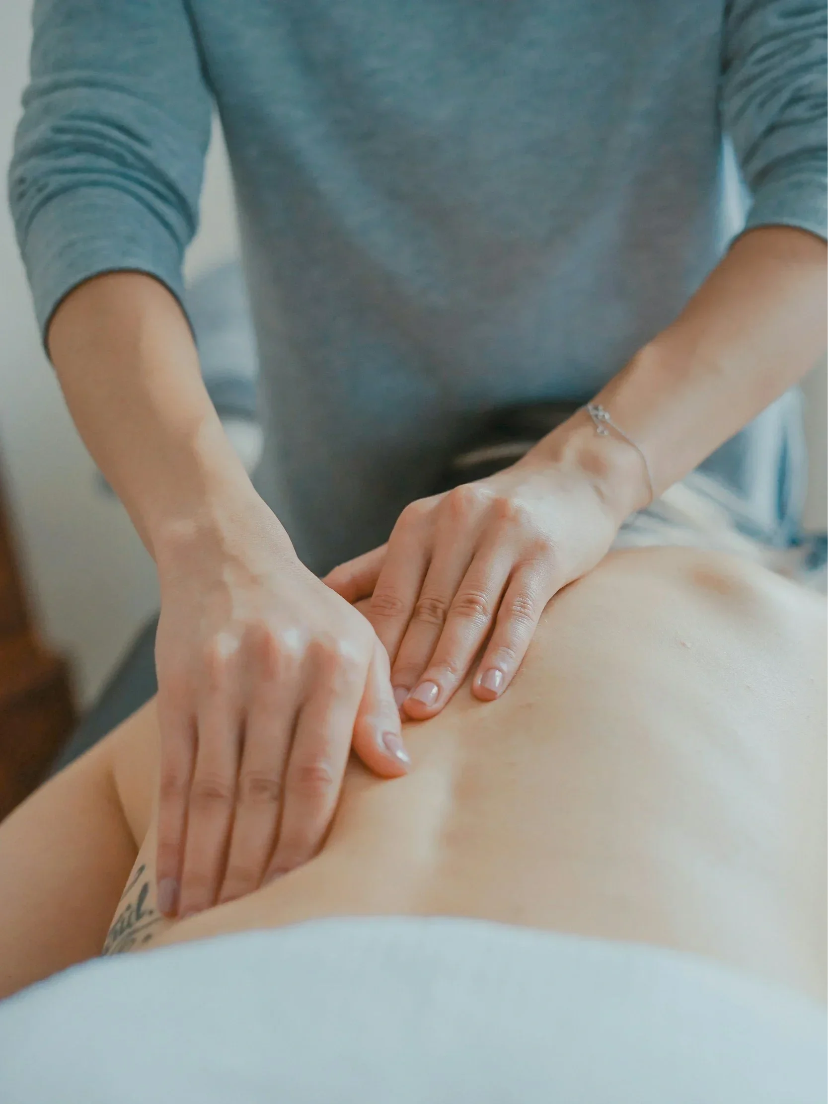 Practitioner performing gentle manual lymphatic drainage on a client’s abdomen.