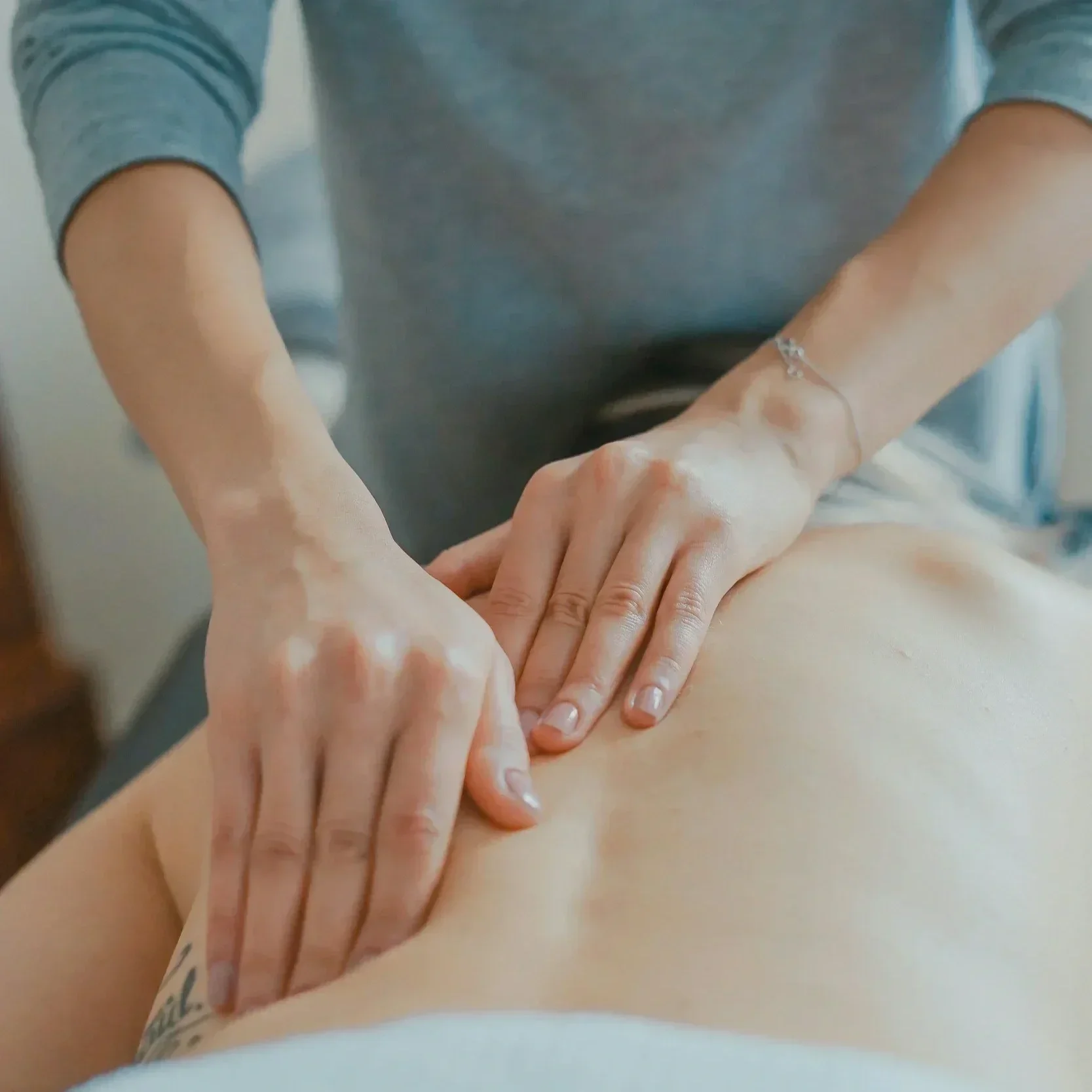 Practitioner performing gentle manual lymphatic drainage on a client’s abdomen.