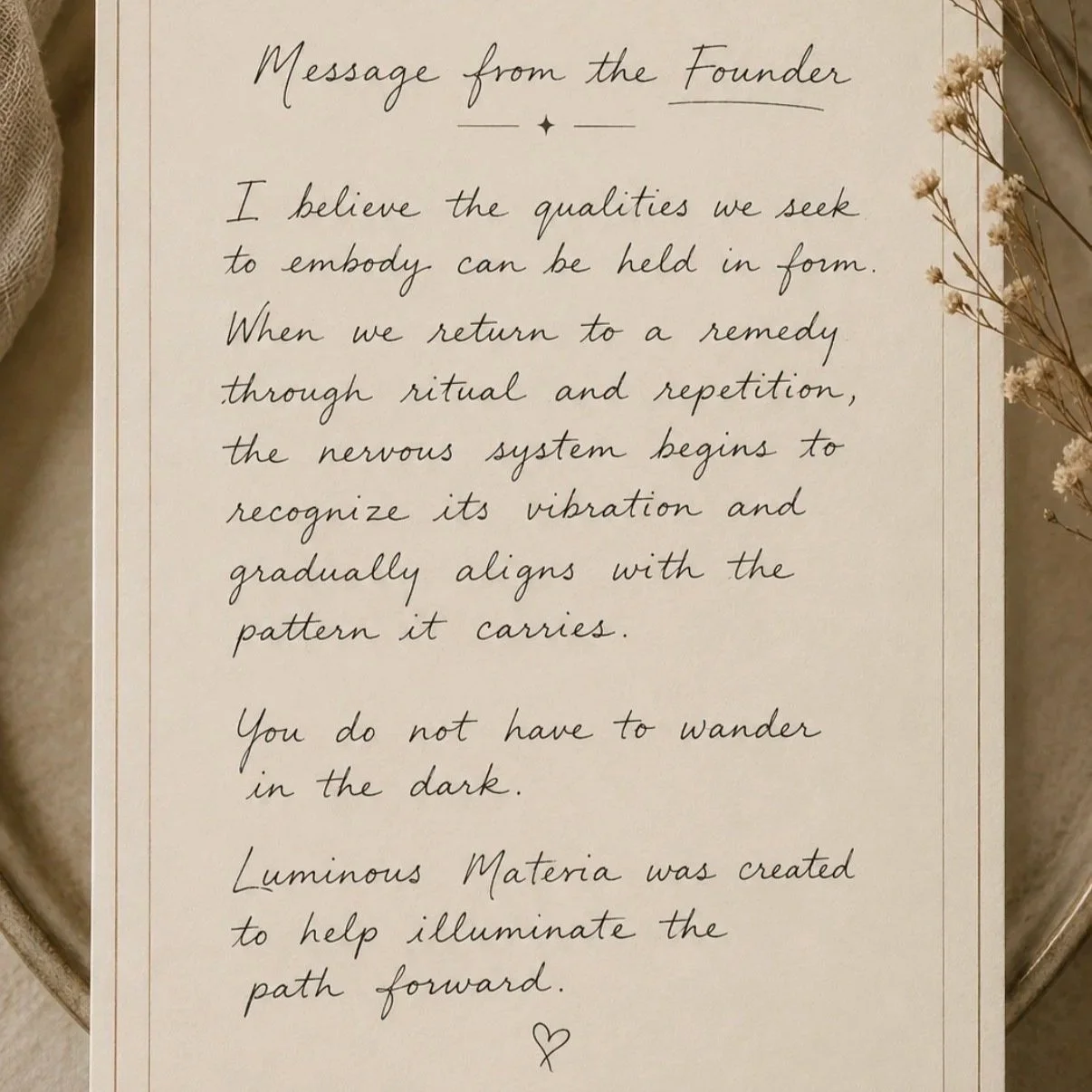 A handwritten message on a beige paper surrounded by dried flowers, with a small heart at the bottom.