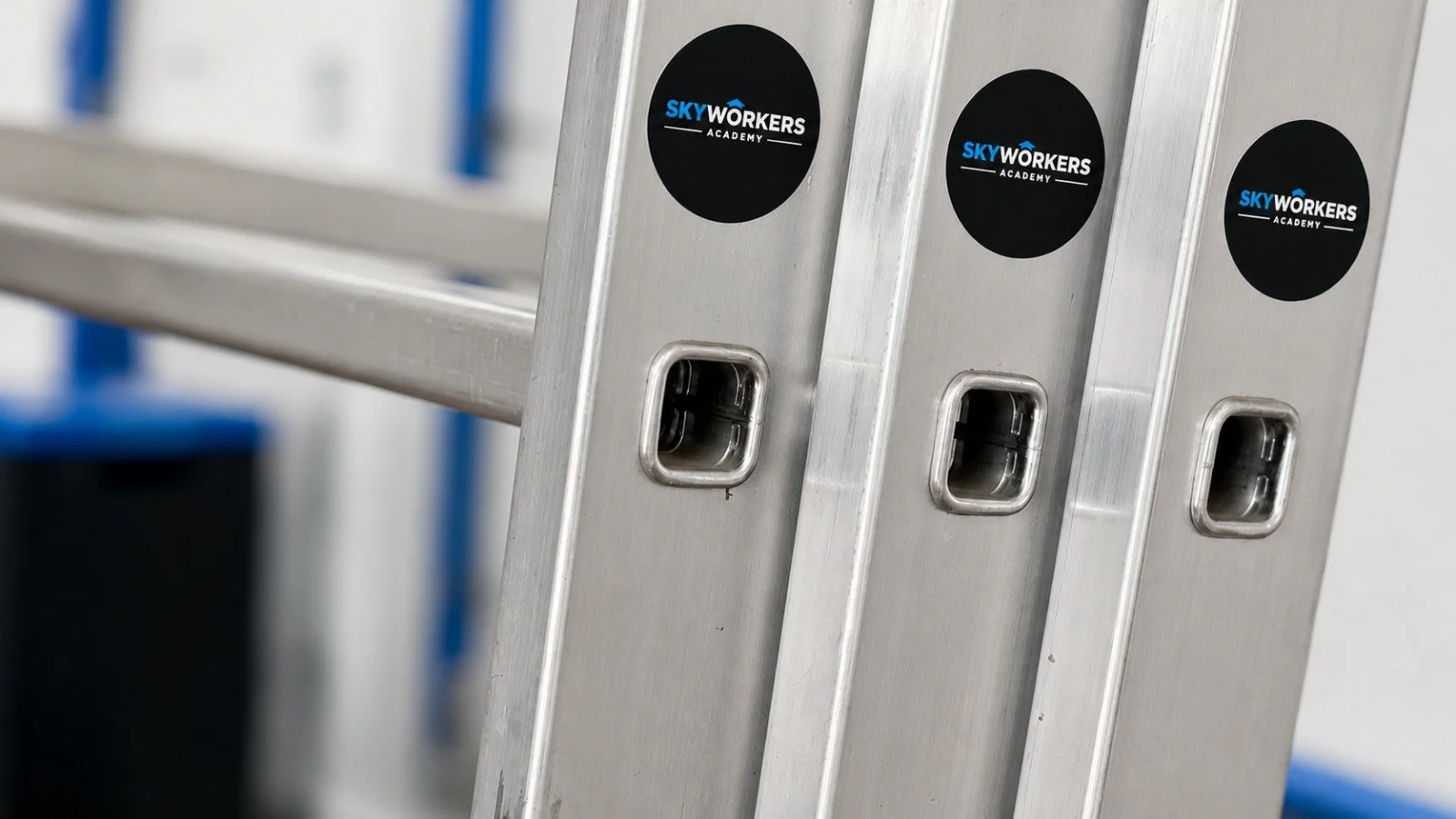 Aluminumleiter mit Aufklebern, die 'Sky Workers Academy' anzeigen.