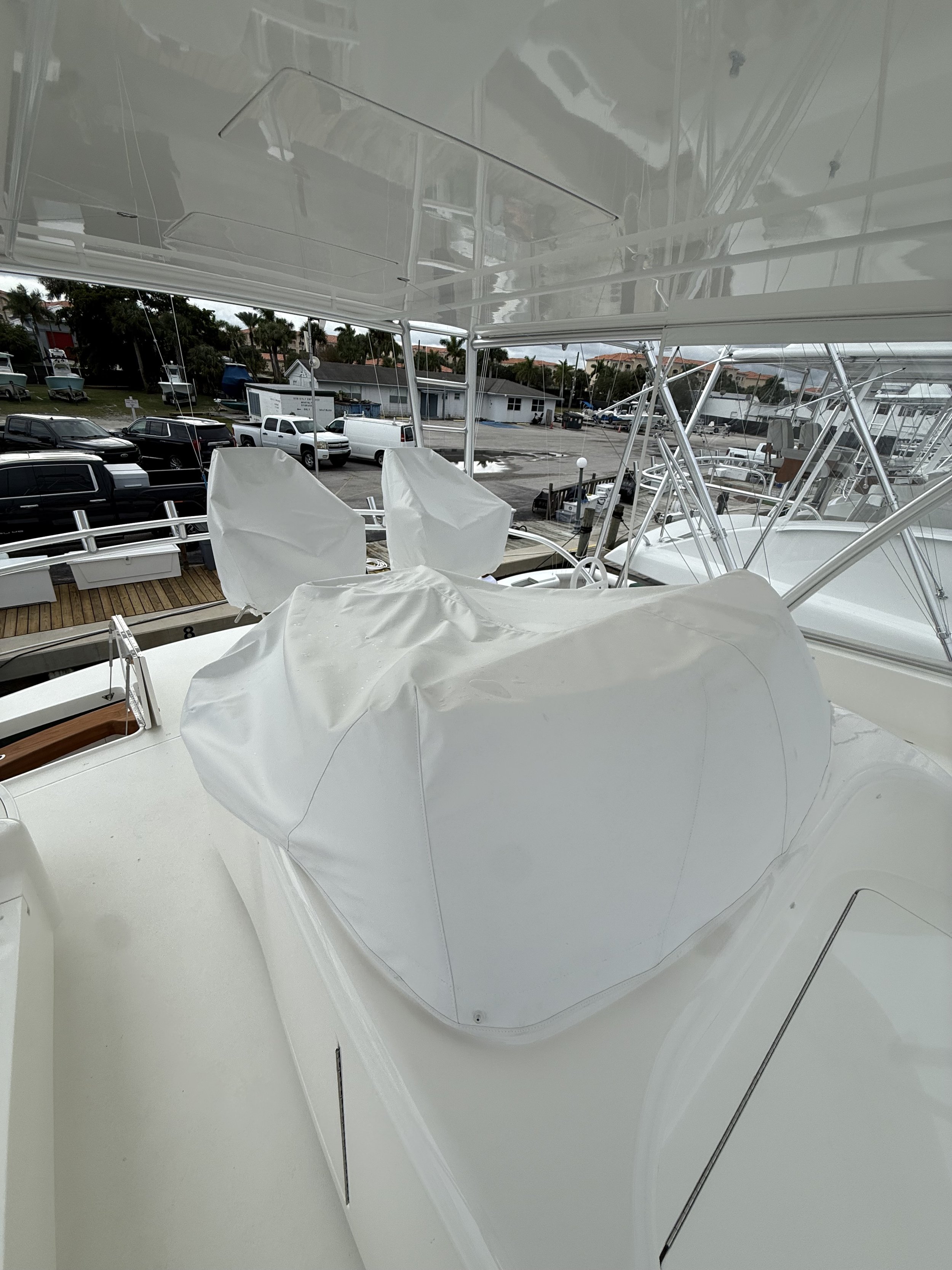 View from inside a boat looking out onto a parking lot with cars, boats, and trees in the background.