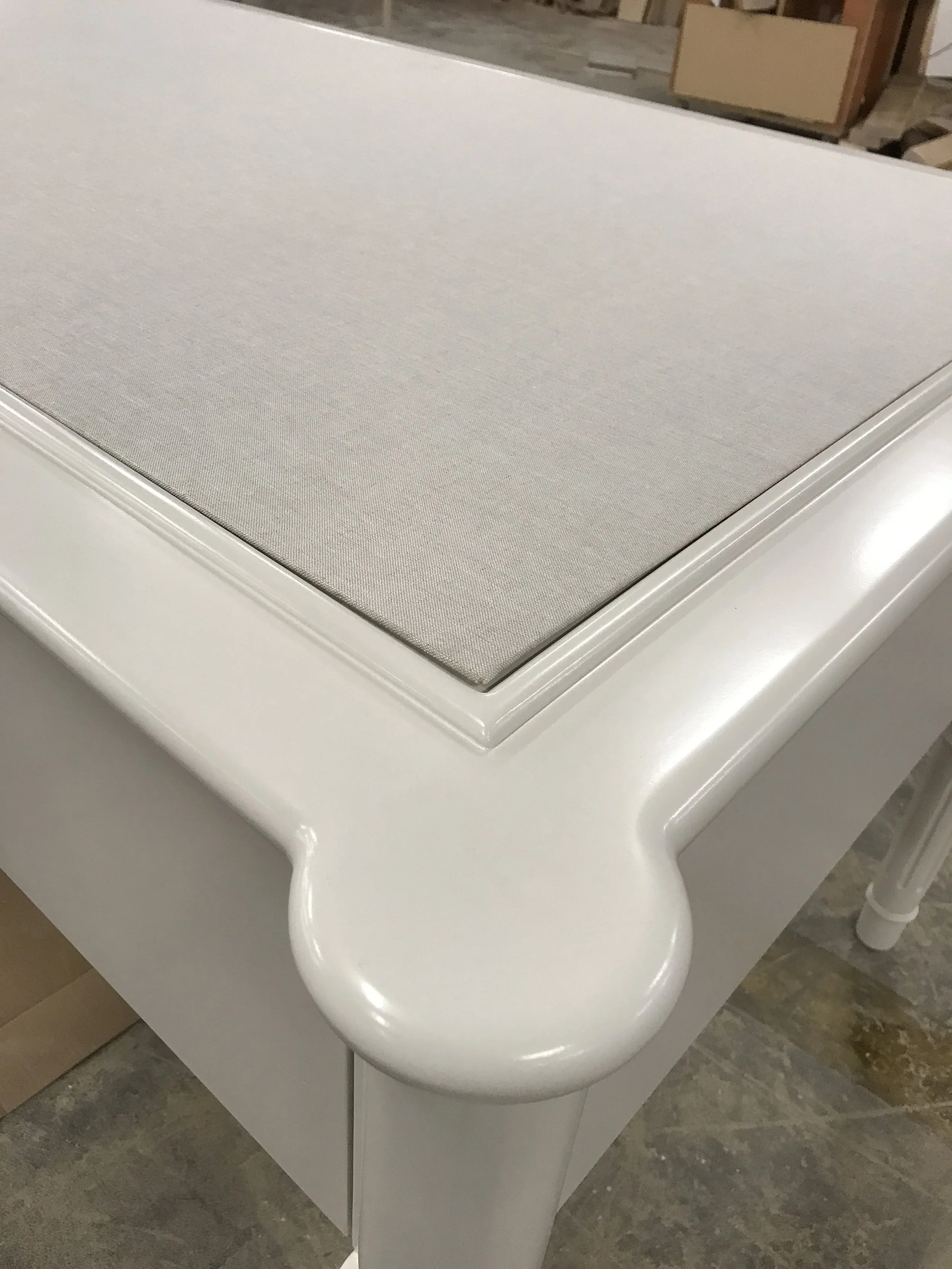 Close-up of a white modern bathroom sink with a textured rectangular countertop and curved supports, taken in a construction or showroom setting.
