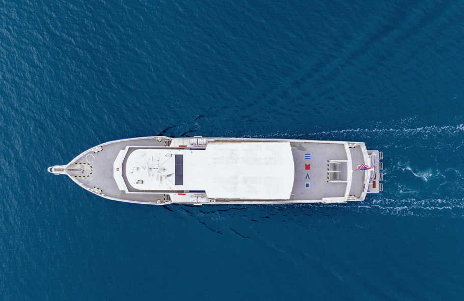 Aerial view of a large white cargo ship sailing on blue ocean water.