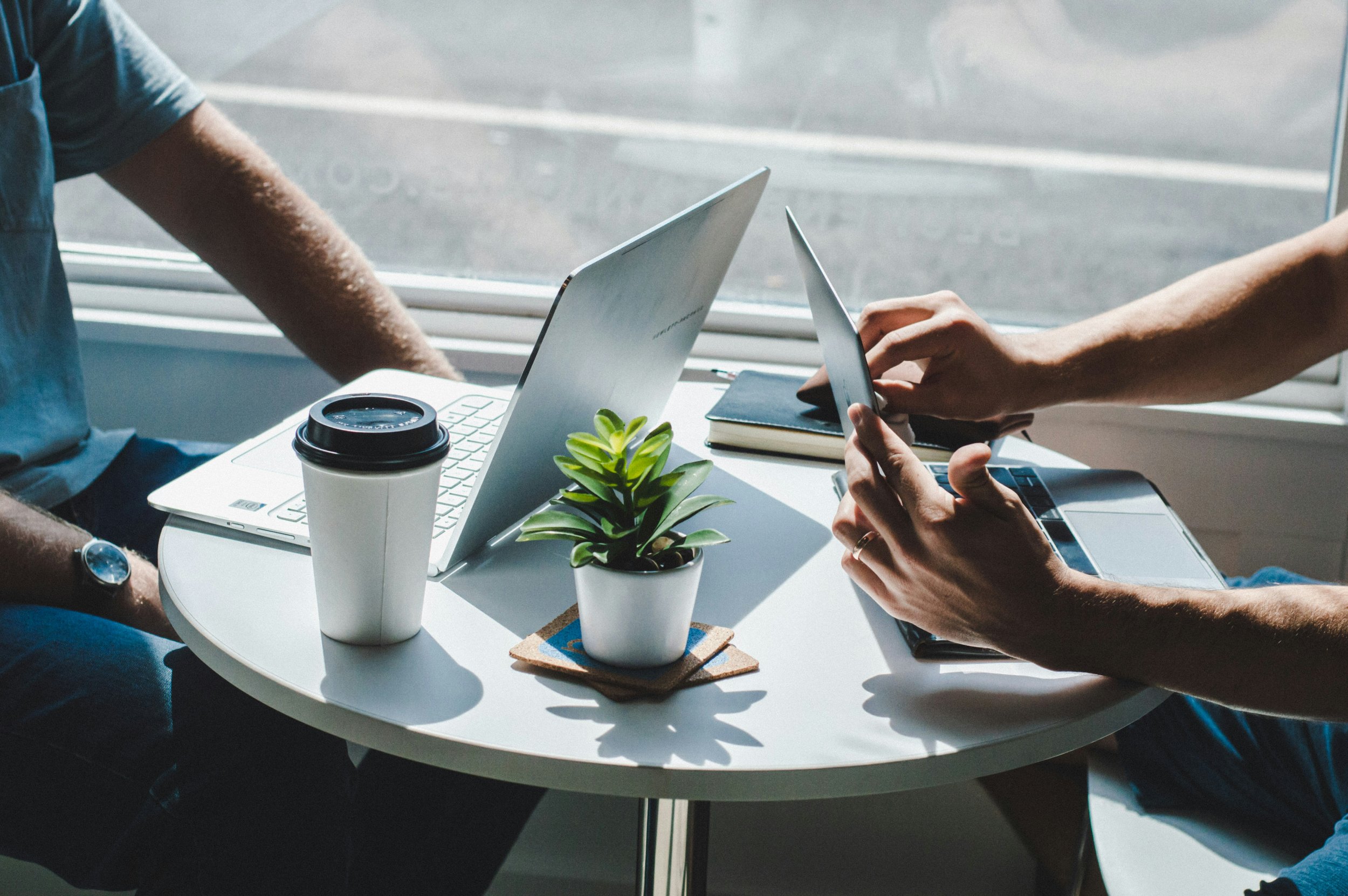 Two people sitting and consulting with laptops
