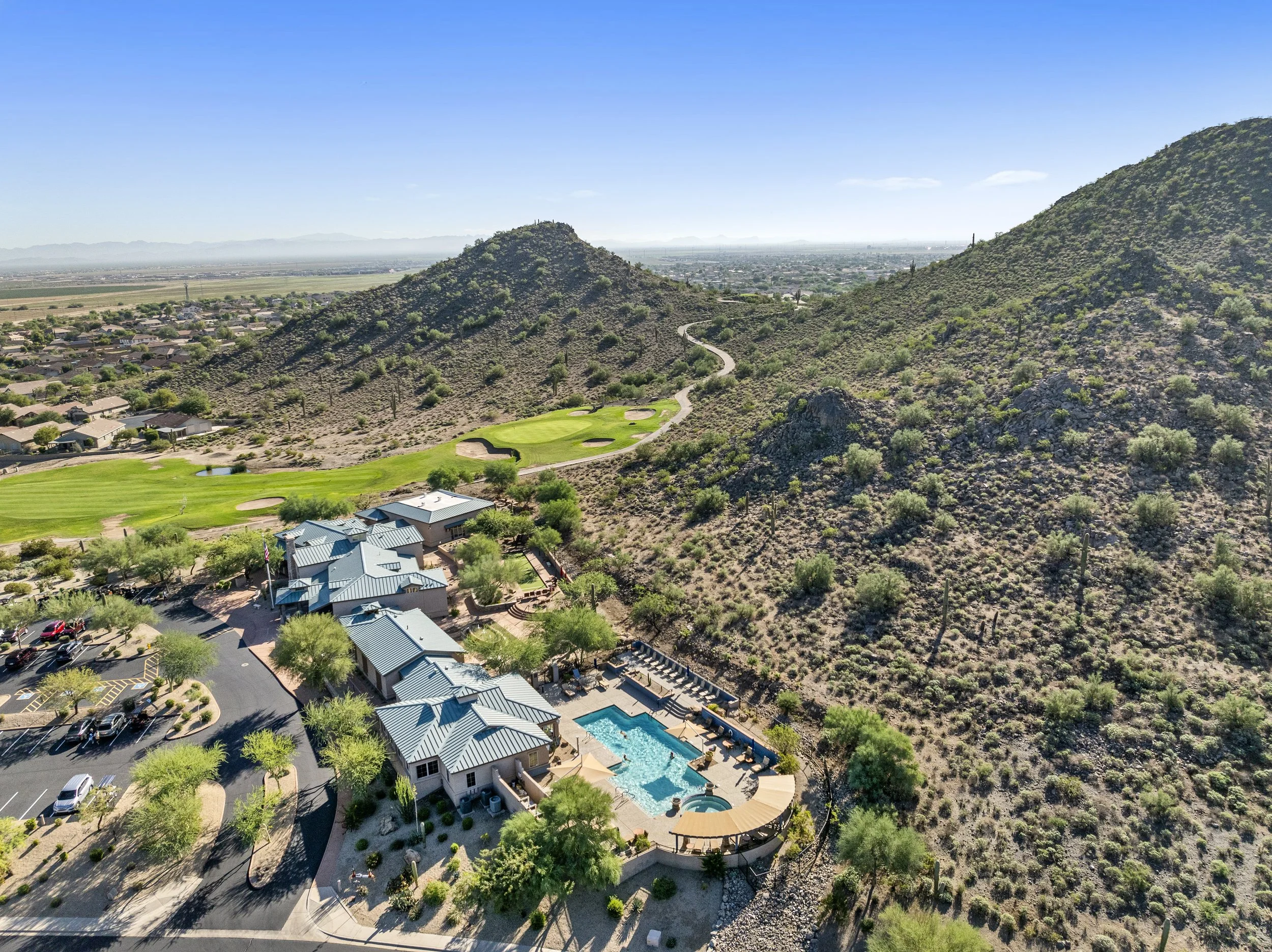 Aerial view of Solera Johnson Ranch clubhouse, resort pool, golf course and mountain backdrop in San Tan Valley, Arizona.