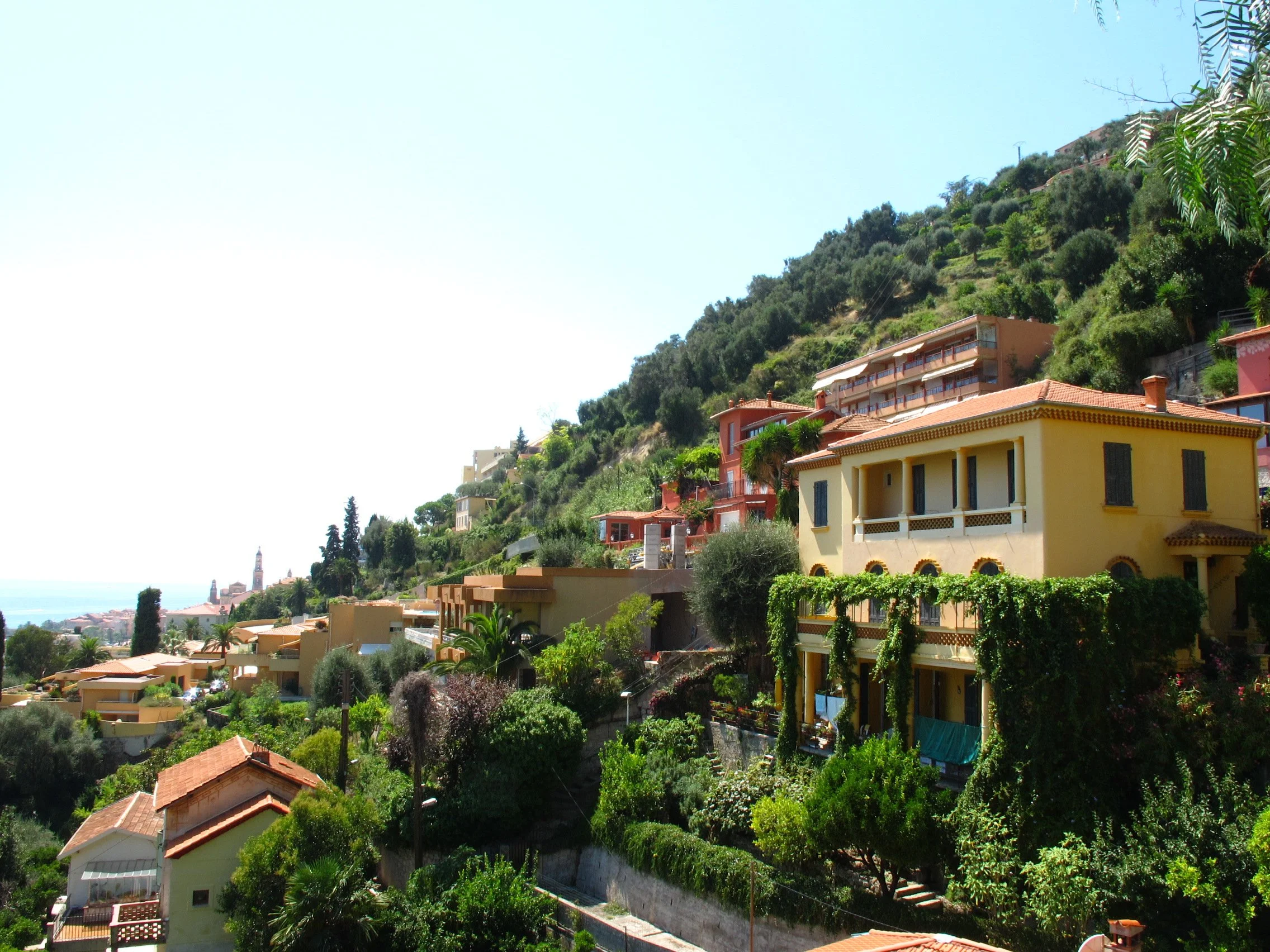 Hilly residential area with colorful houses and lush greenery under a clear blue sky.