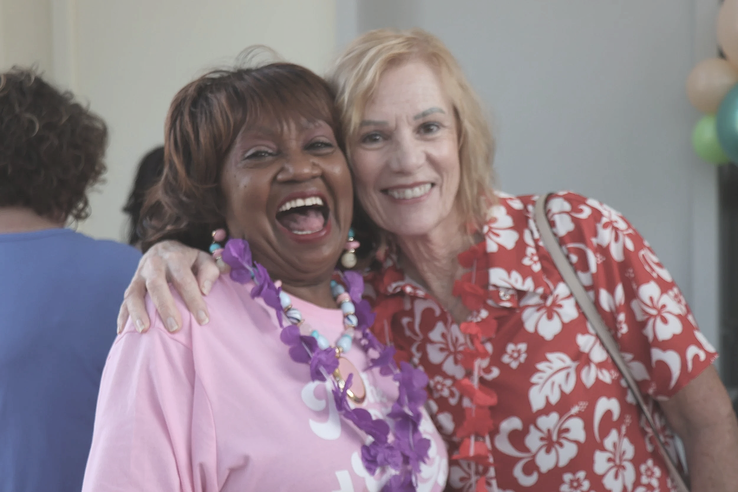 Two older women smiling and laughing while posing for a picture
