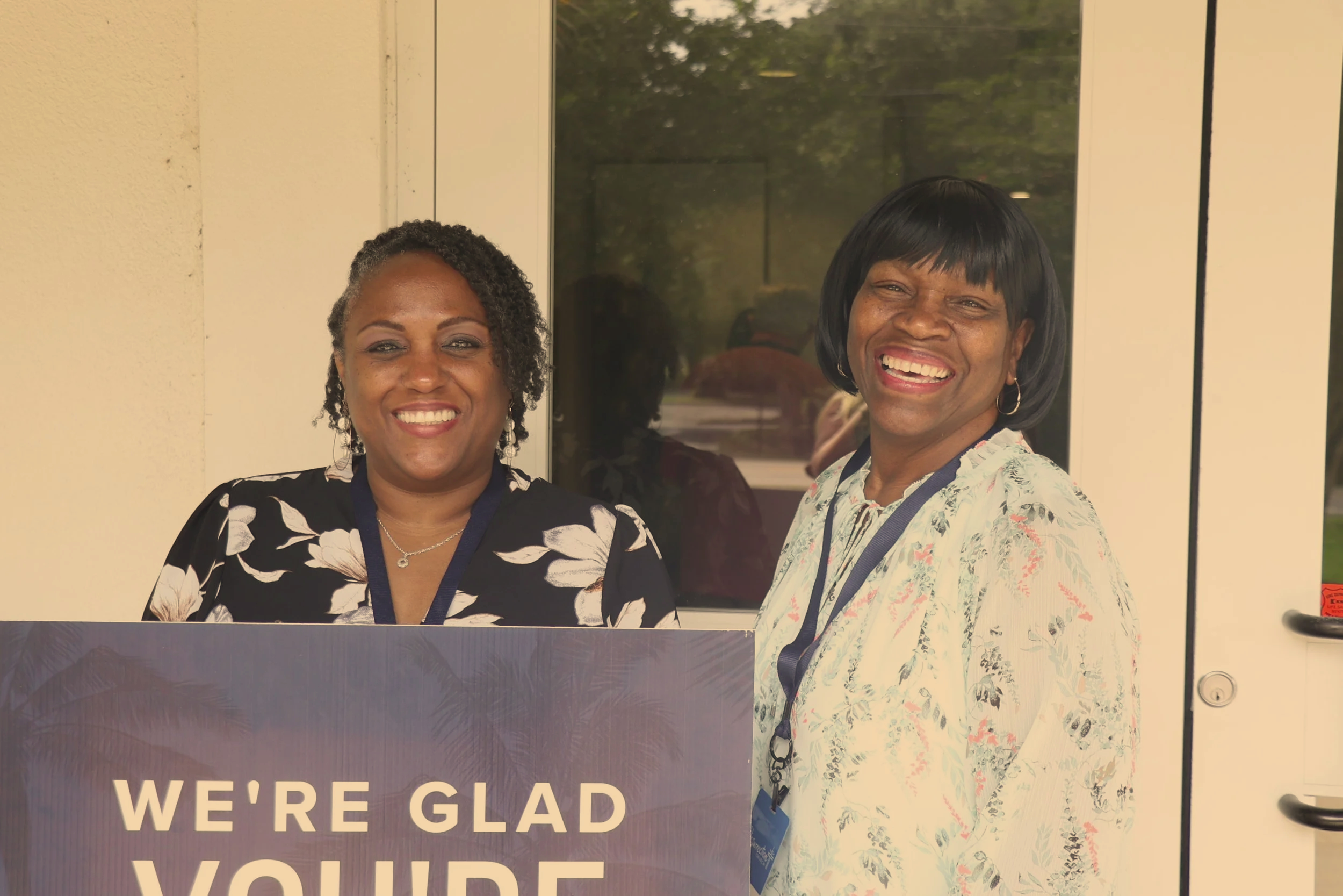 Two women smiling and serving in front of doors