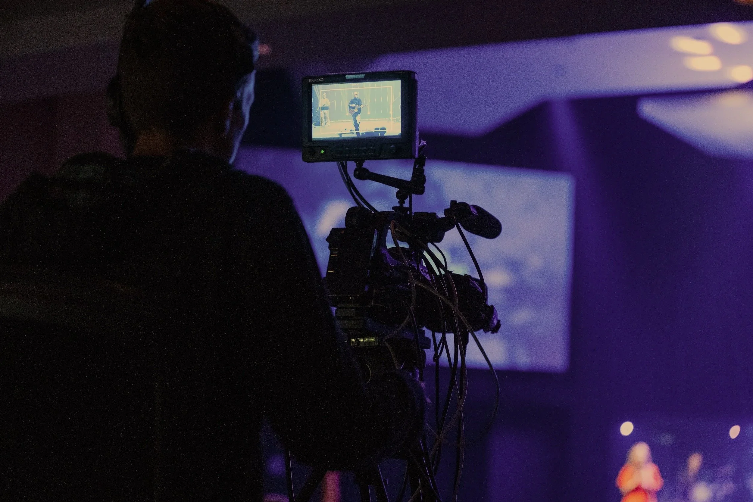 A man in dark clothing operating a camera in a worship servie