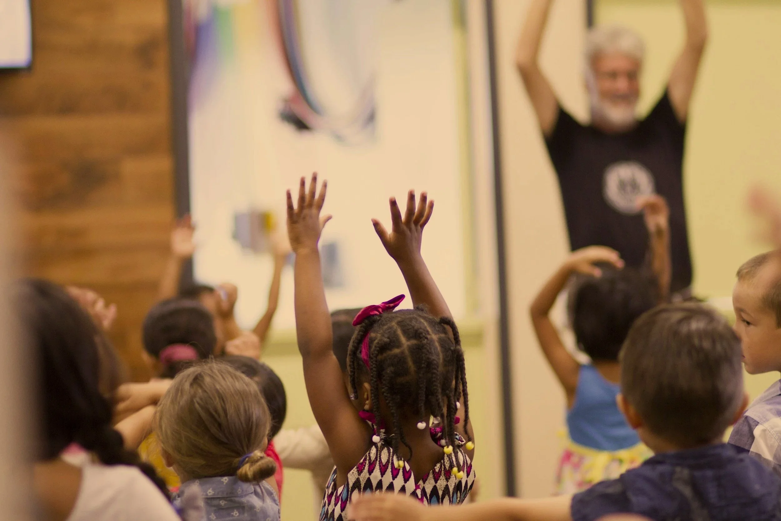Young kids in a children's service one little girl raising her hands in worship