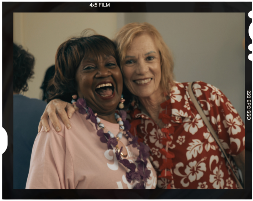 Two older ladies smiling and standing next to each other who look very happy