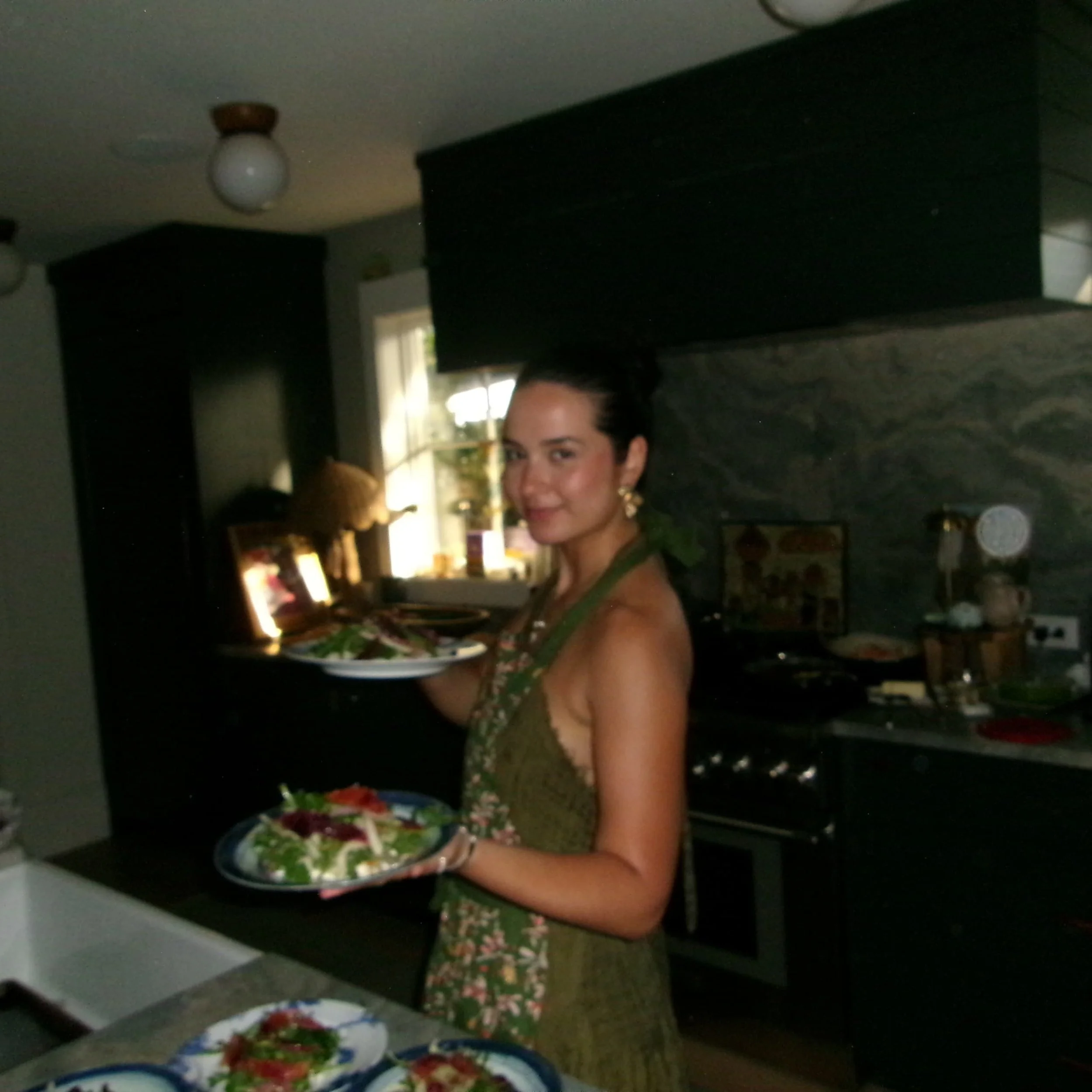 Chef Bella smiling while preparing fresh ingredients in a kitchen for an in-home dining experience