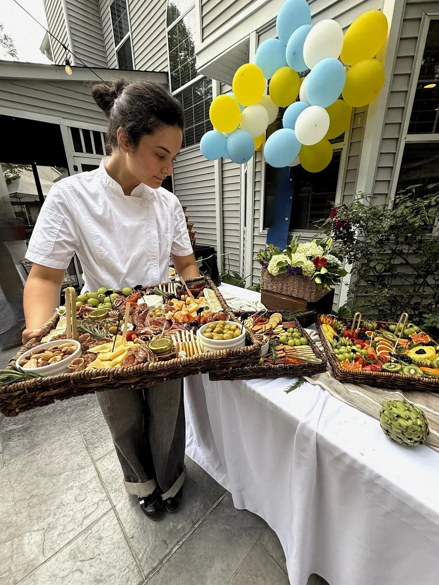 Chef Bella holding a curated charcuterie board with fresh fruits, cured meats, and cheeses at a catered event in Charleston, South Carolina.