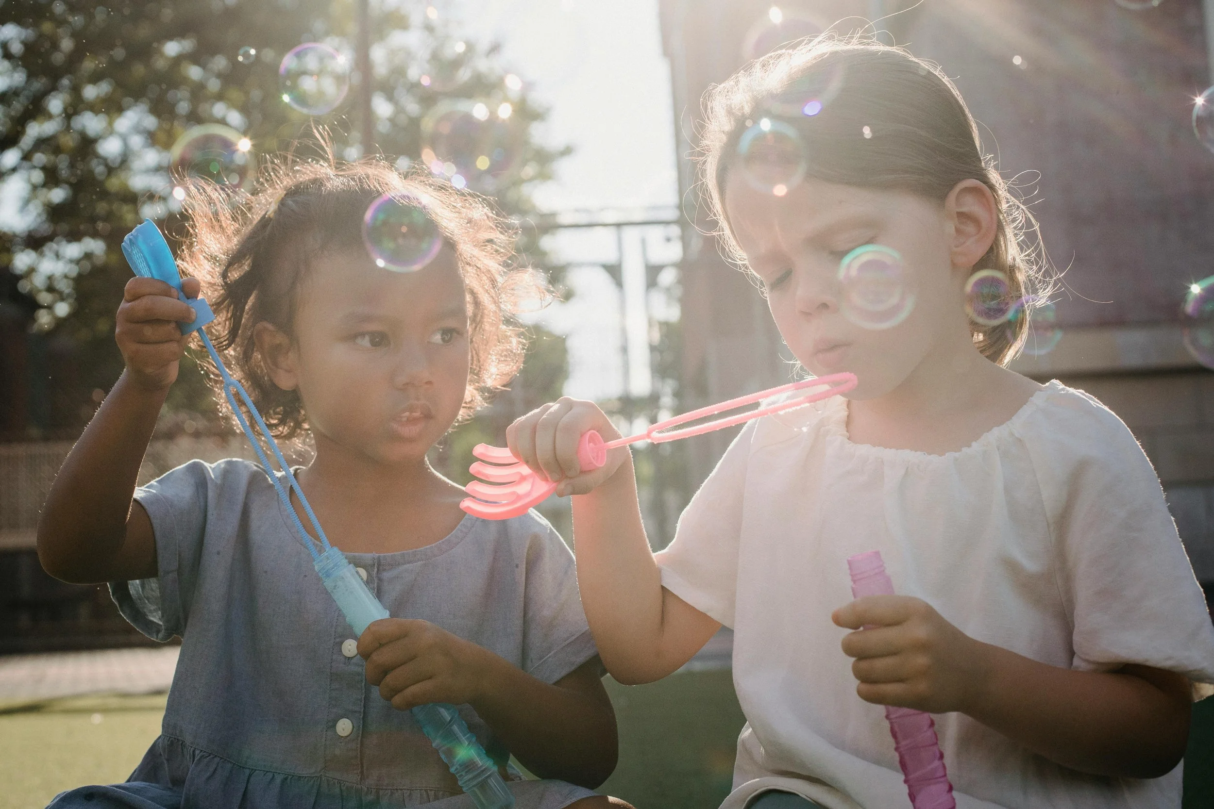 Deux jeunes enfants qui parlent et qui soufflent des bulles avec plaisir pour développer leur langage et leur communication dans un environnement naturel à La Prairie