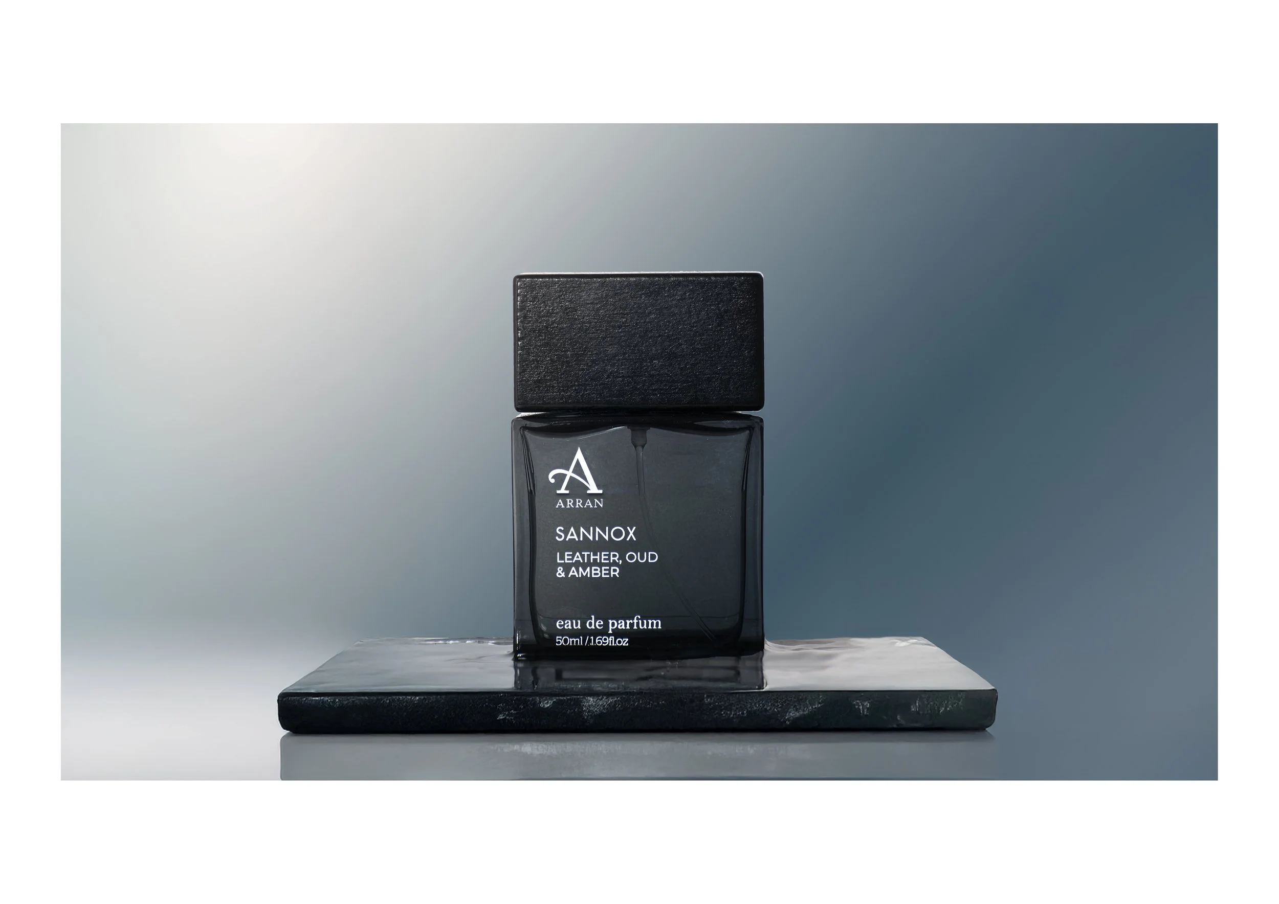 A black perfume bottle on a black marble stand with a white surface and gradient background