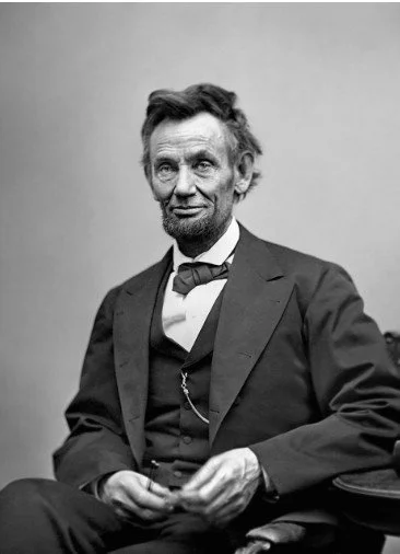 Un portrait en noir et blanc d'un homme habillé en 19e siècle, portant un costume formel, une cravate et une montre à gousset, assis contre un fond simple.