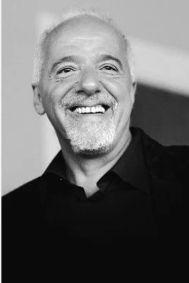 portrait d'un homme souriant avec une barbe grise, en noir et blanc