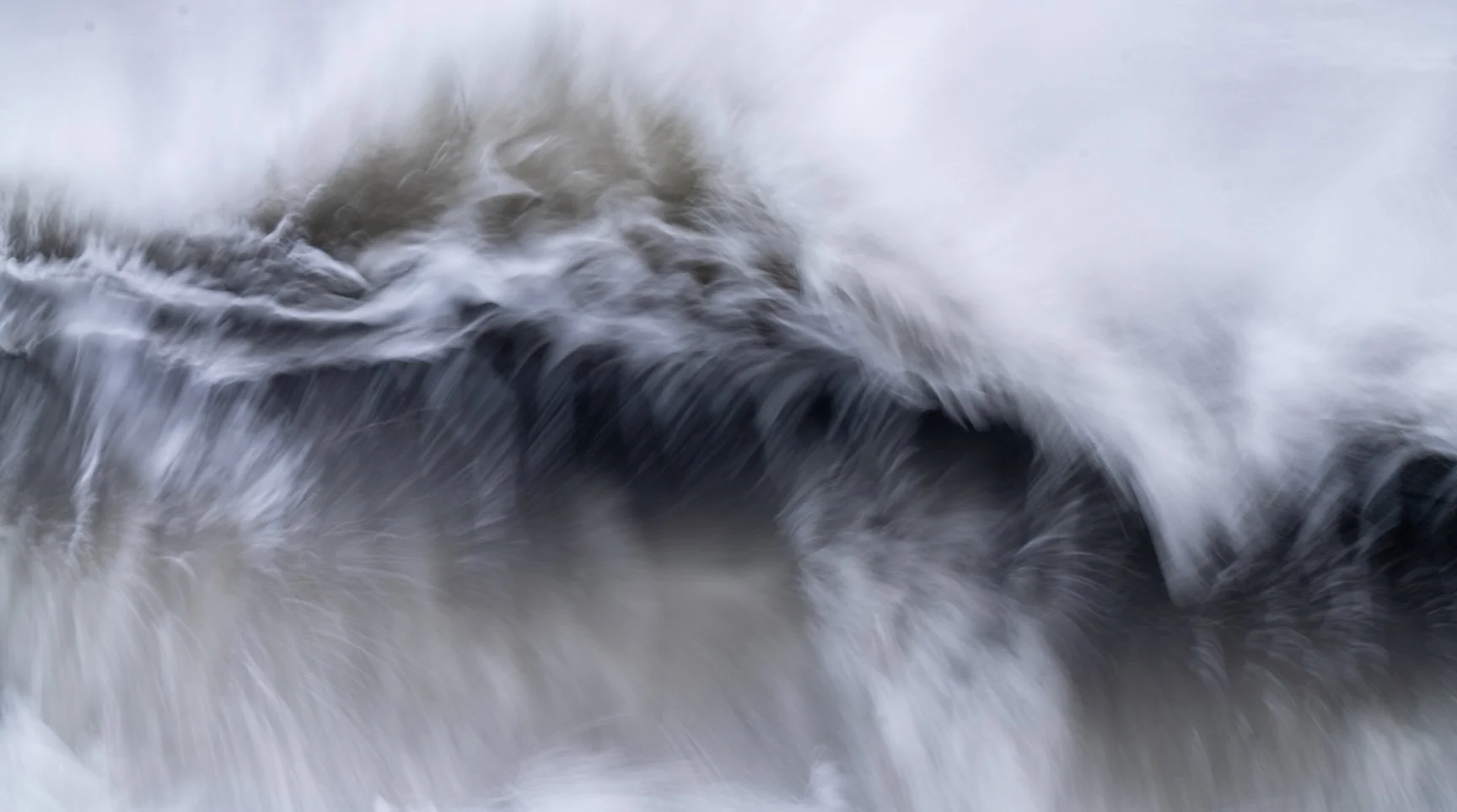 Close-up of water swirling and rushing over rocks in a fast-moving stream or river.