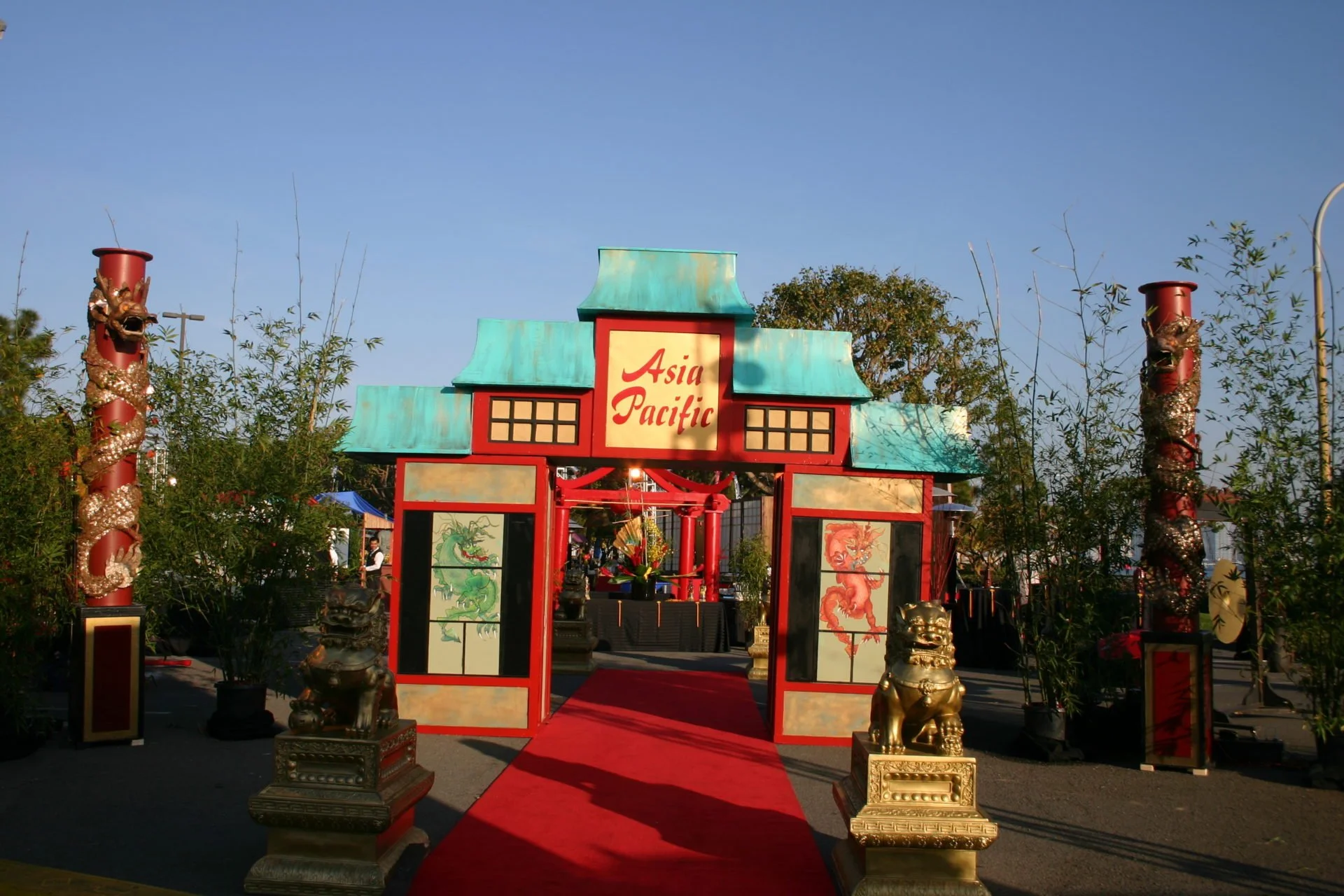 Entrance arch with Asian-themed decorations, including golden lion statues and dragon pillars, leading to a celebration area with 'Asia Pacific' sign.