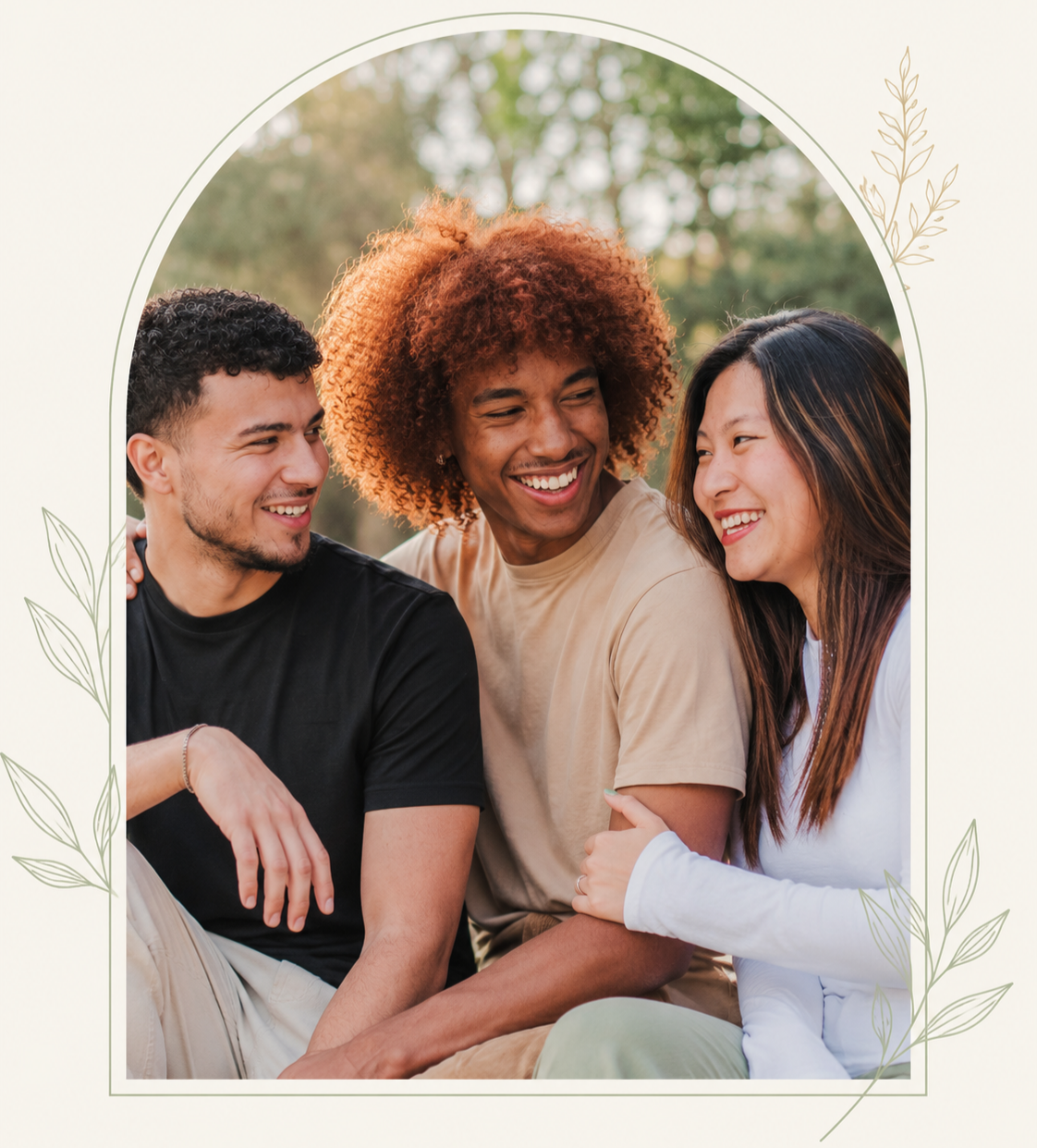 Three friends sitting close together outdoors, smiling and laughing during the daytime.